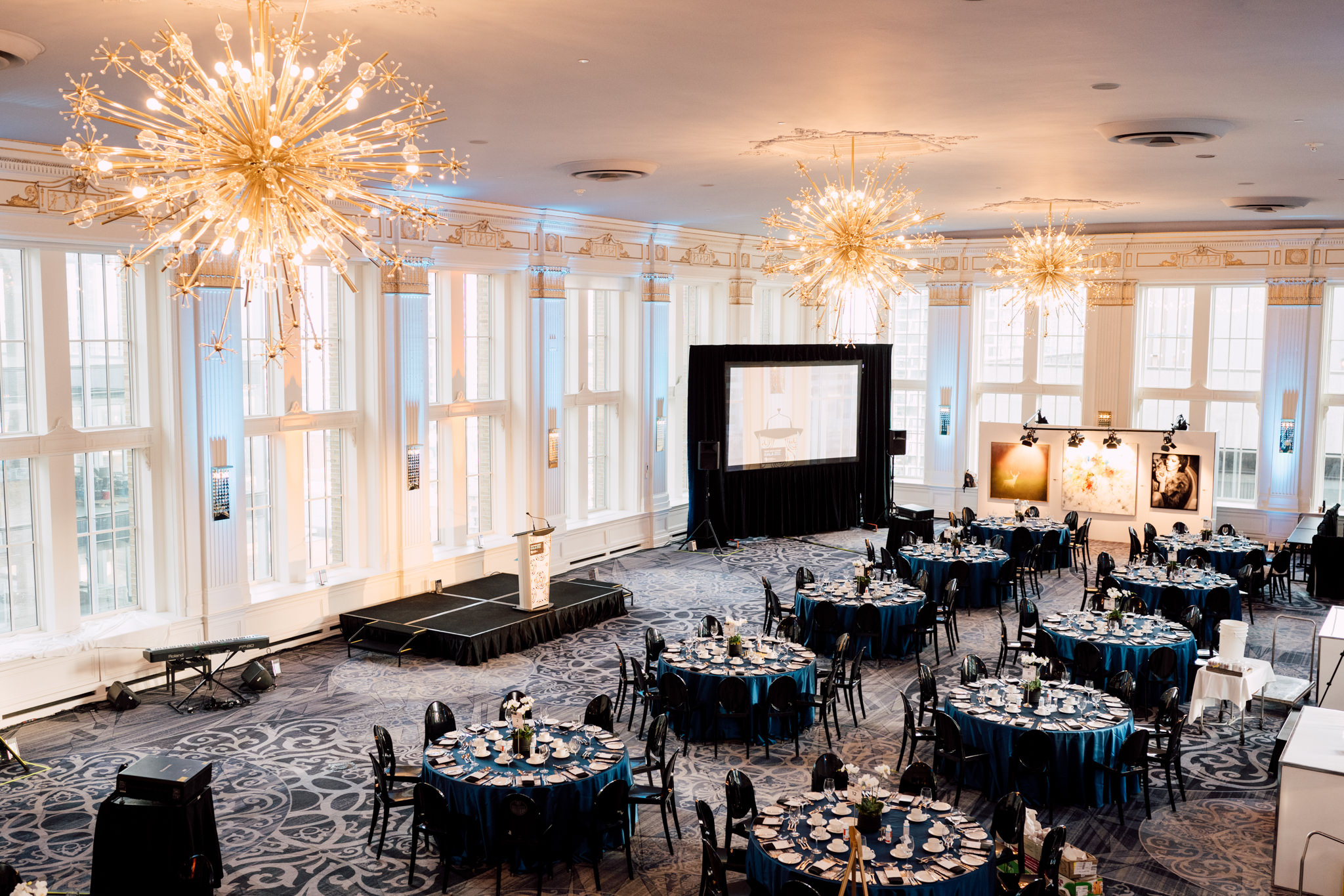 Large ballroom, blue tables, chandeliers.