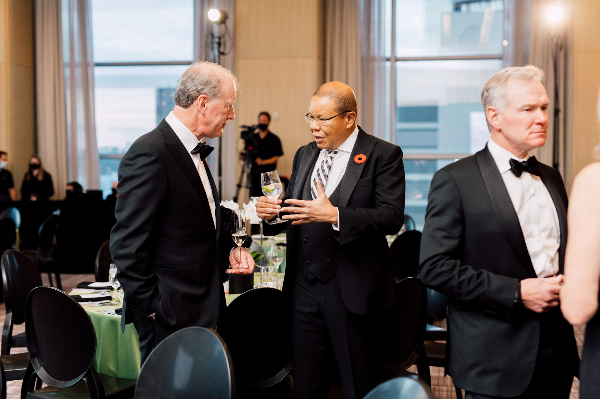 Three men in formal attire conversing at a gathering.