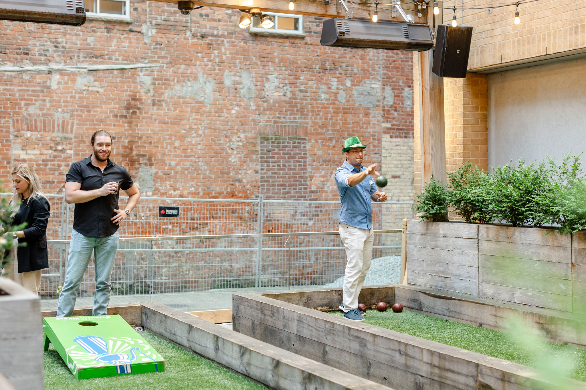 Social event photography of two men playing a game of cornhole in a backyard.