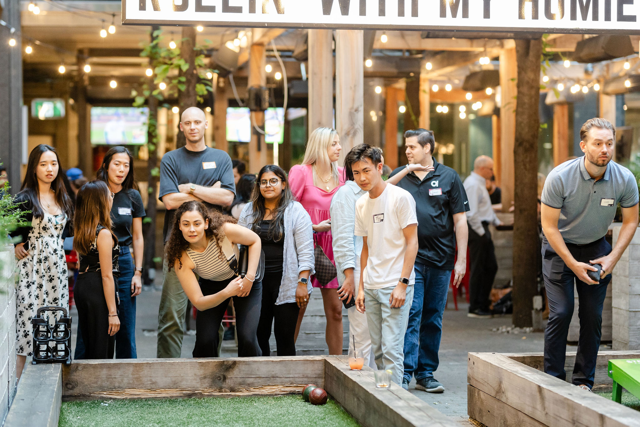 A group of people participating in a social event playing shuffleboard.