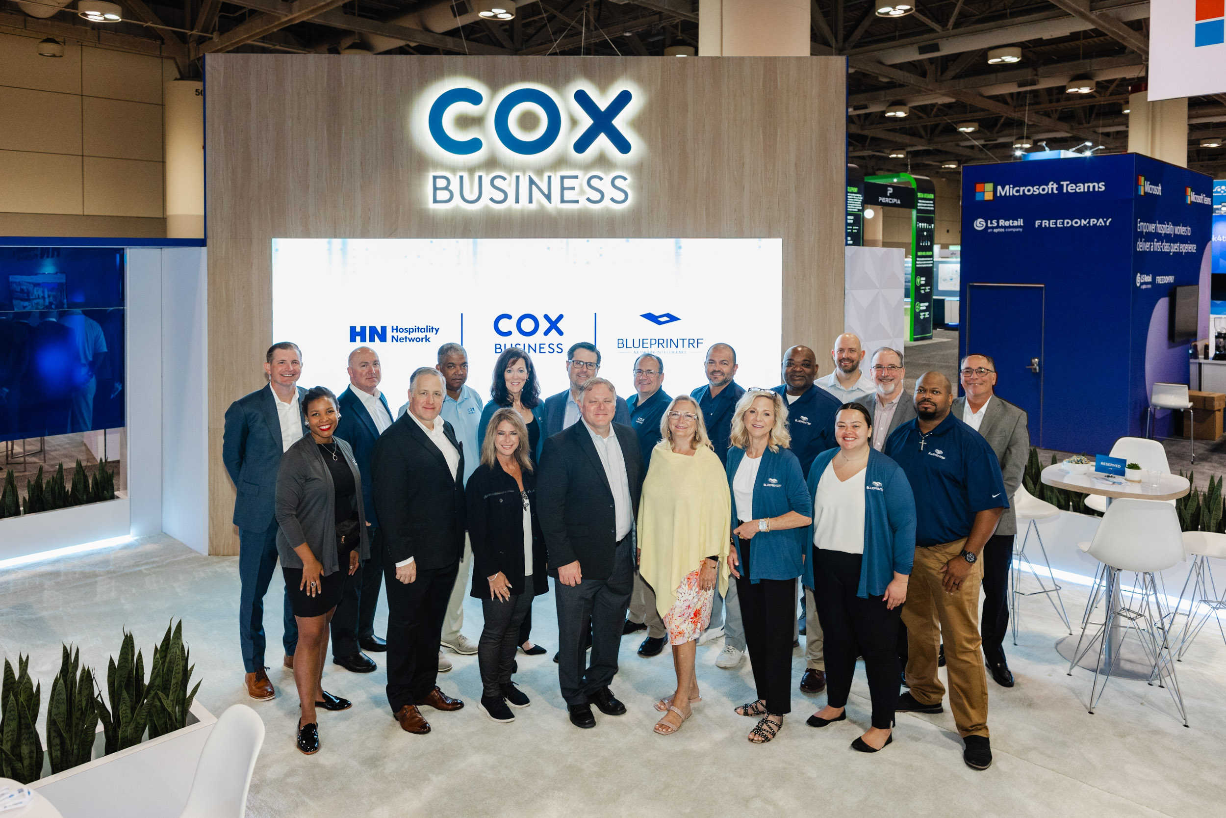 A group of people standing in front of a Cox Business booth at a Toronto trade show.