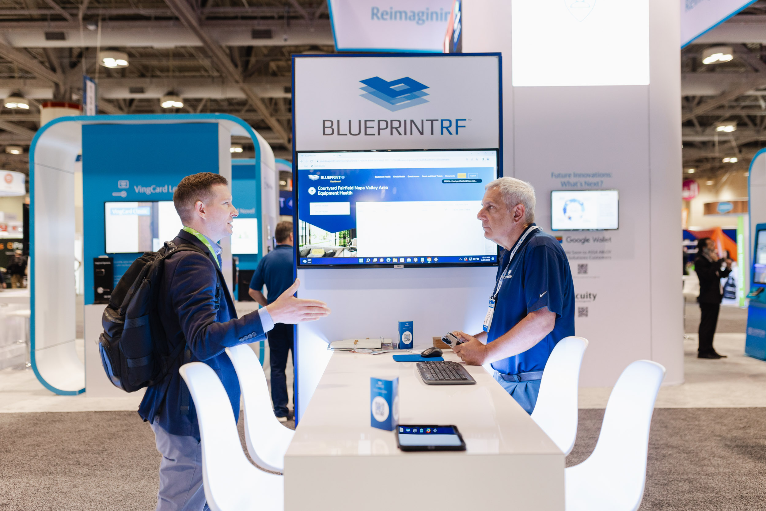Two individuals discussing at a blueprint booth during a Toronto trade show.