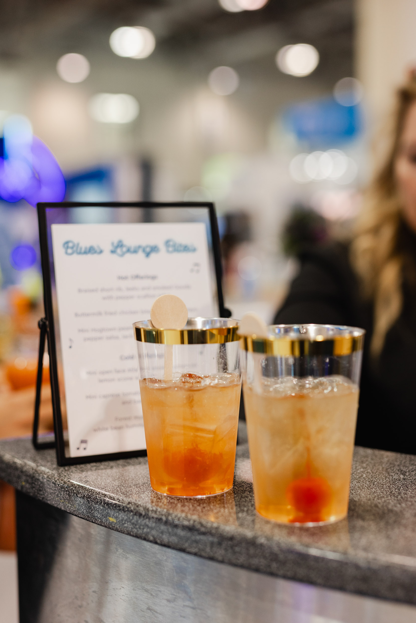 Photography captures two beverages displayed on a counter at a lively Toronto trade show.