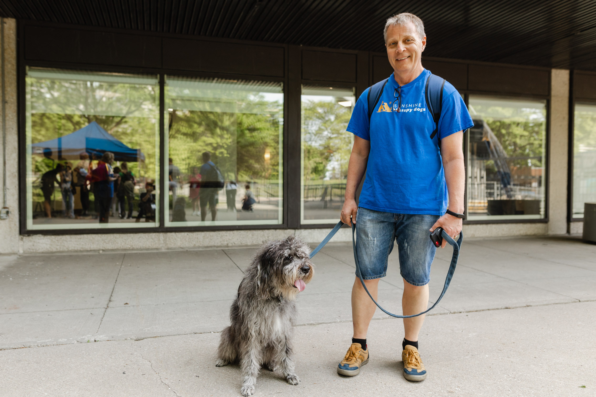 A man at a conference with a dog on a leash.