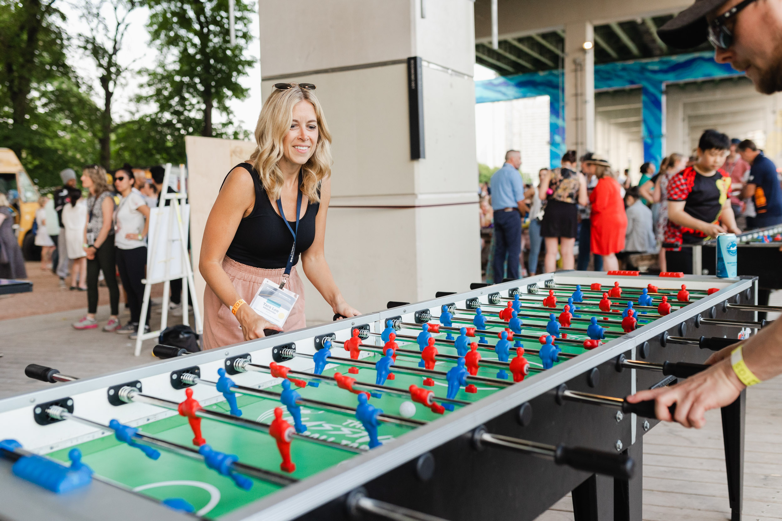 A group of people playing foosball at an outdoor conference event.