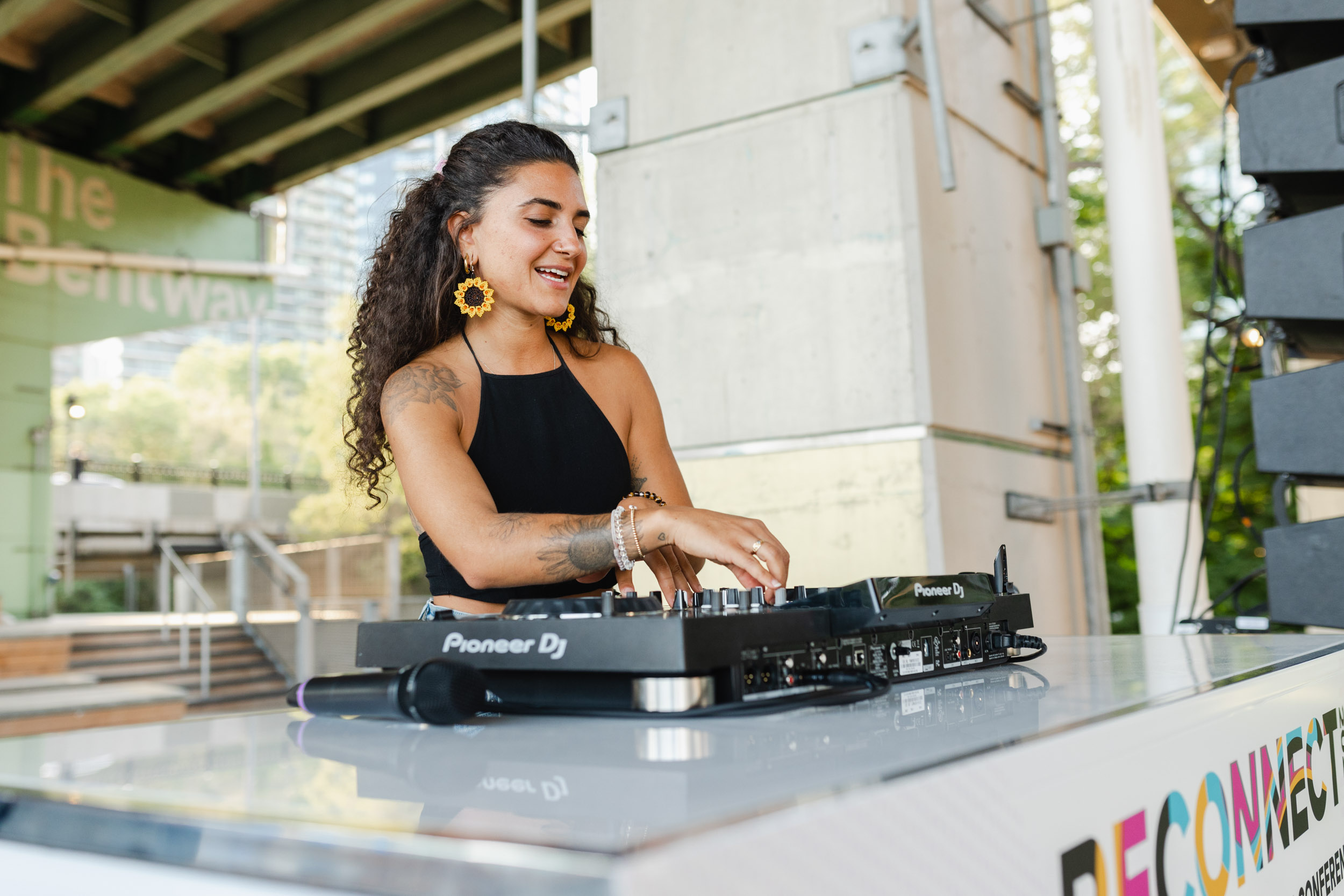 A woman performing as a DJ at an outdoor conference.