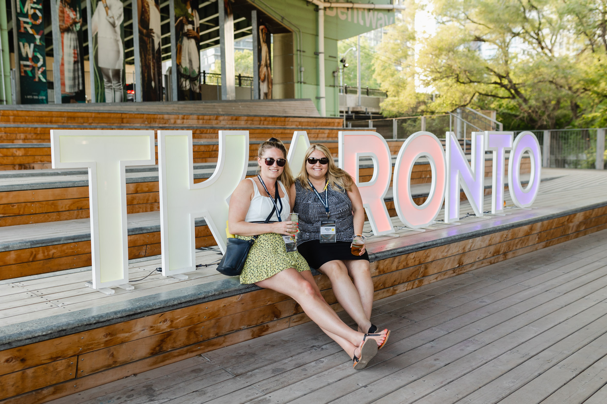 Two women at a conference in front of a sign that says Toronto.
