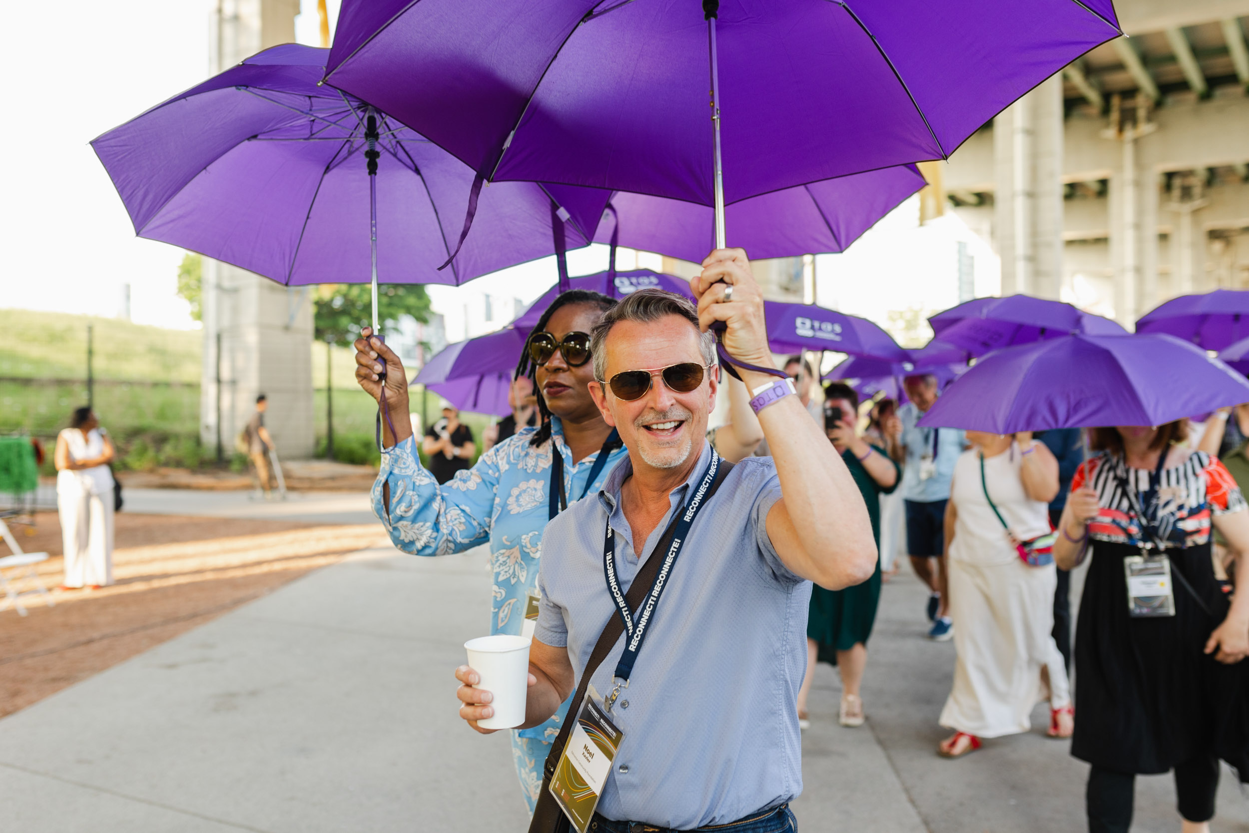Conference attendees holding purple umbrellas.