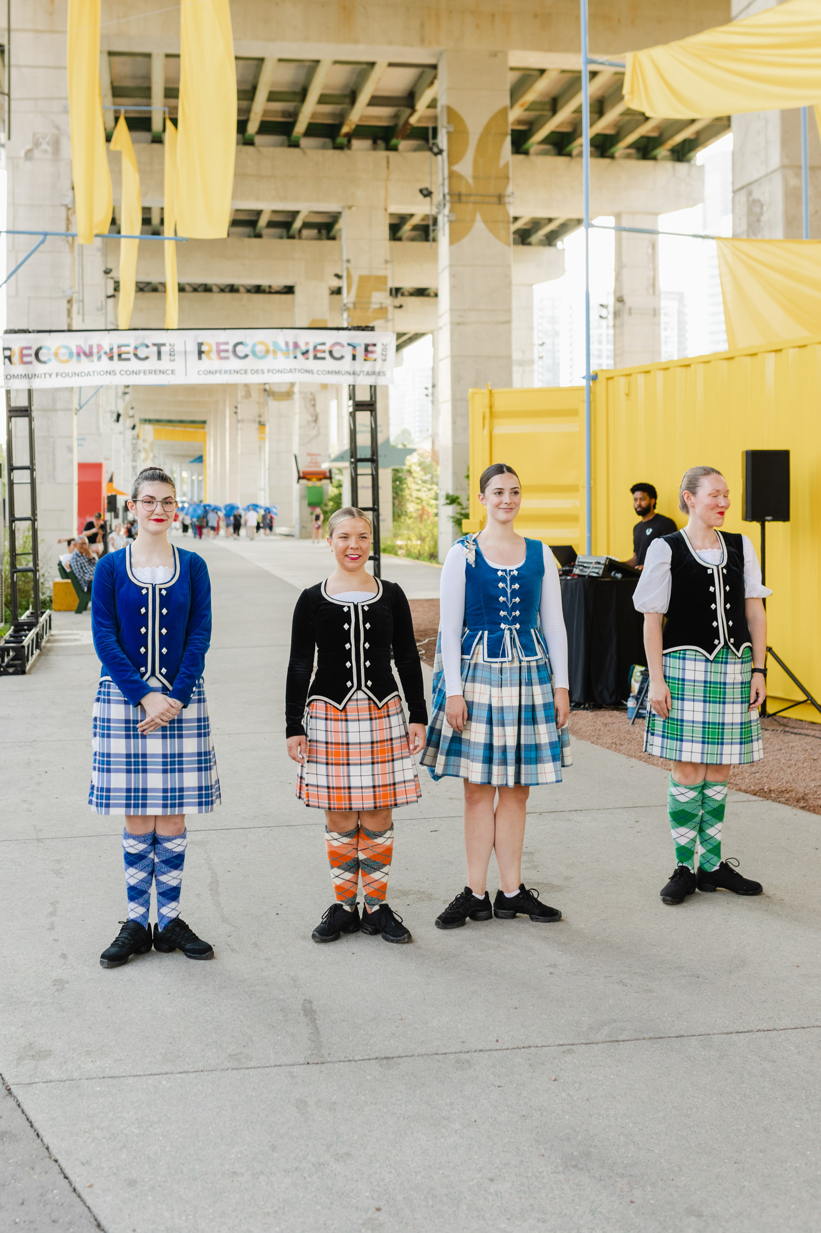 Conference photographers capture Scottish dancers in kilts standing in front of a building.