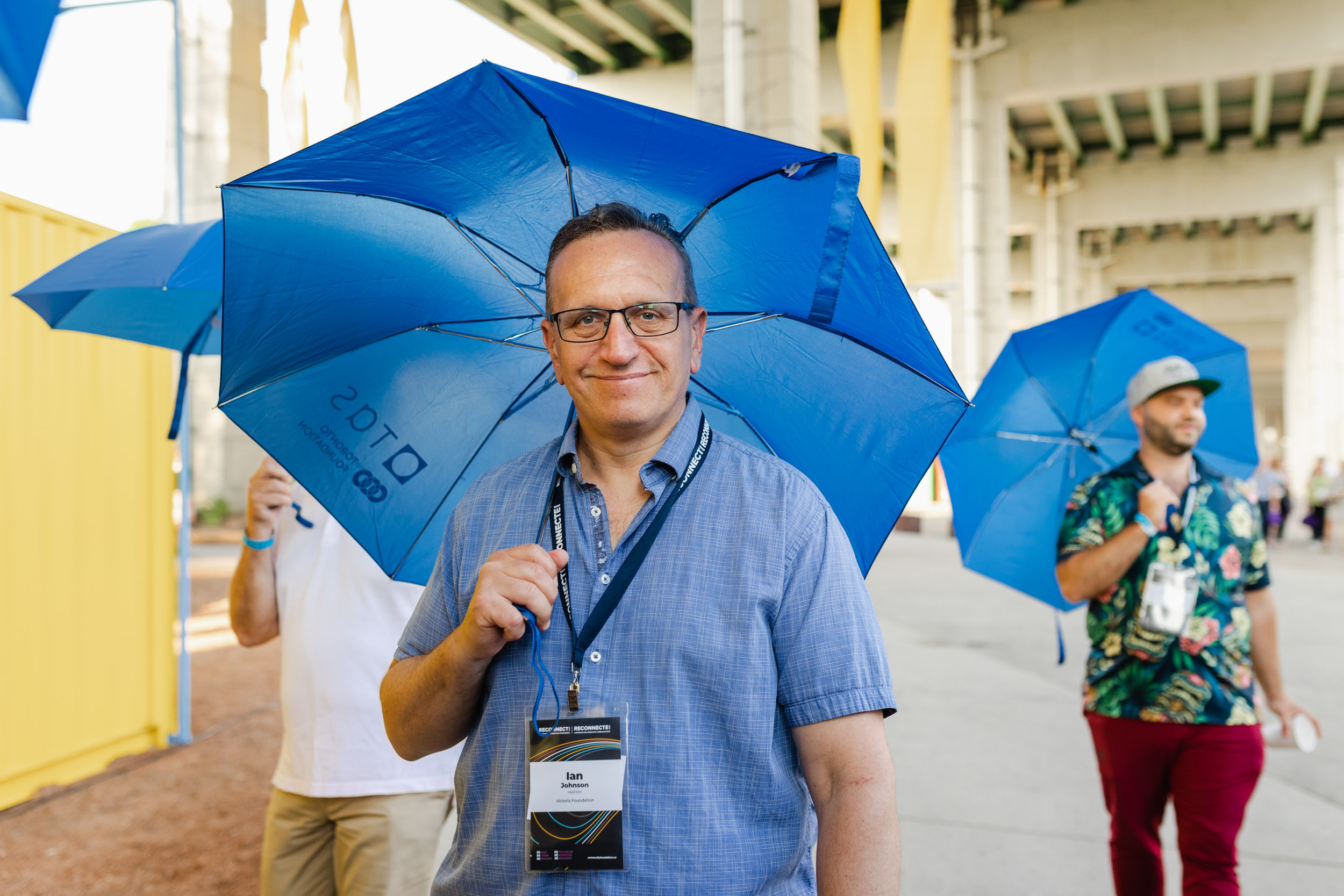 A man holding a blue umbrella at a conference.
