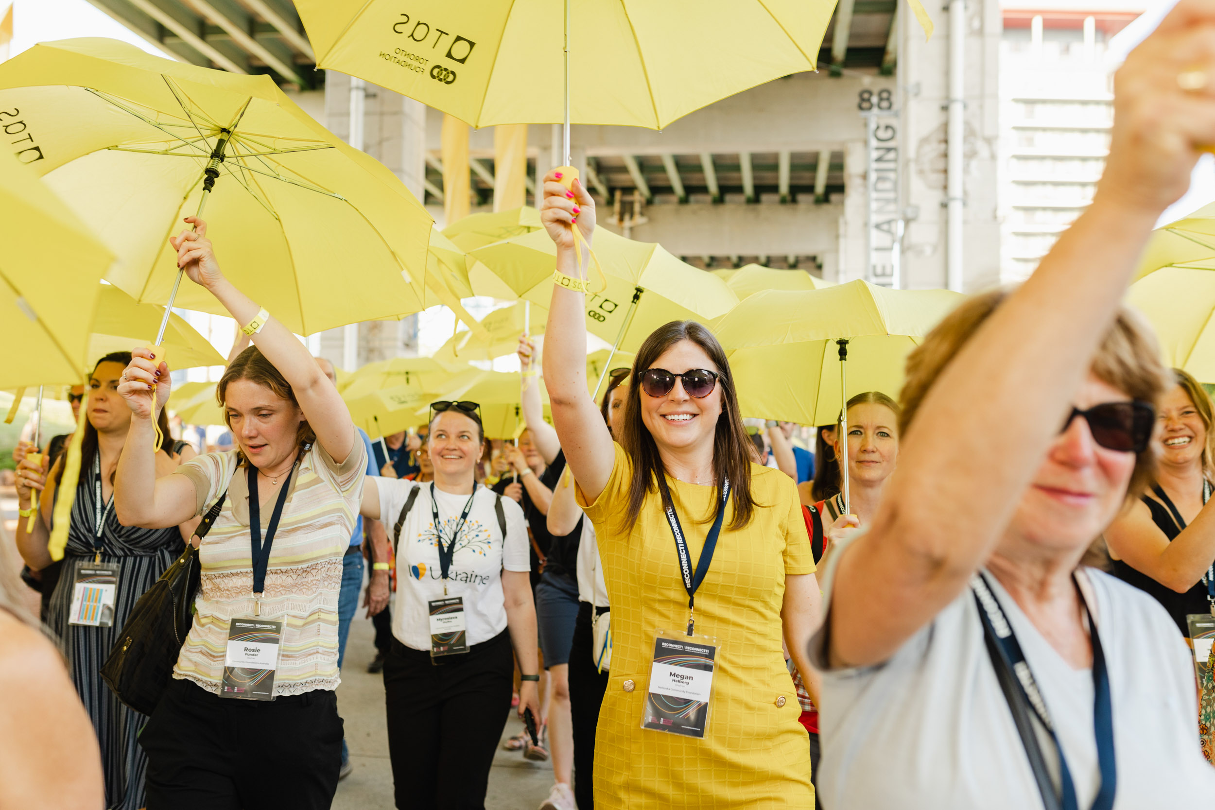 Conference attendees holding yellow umbrellas.