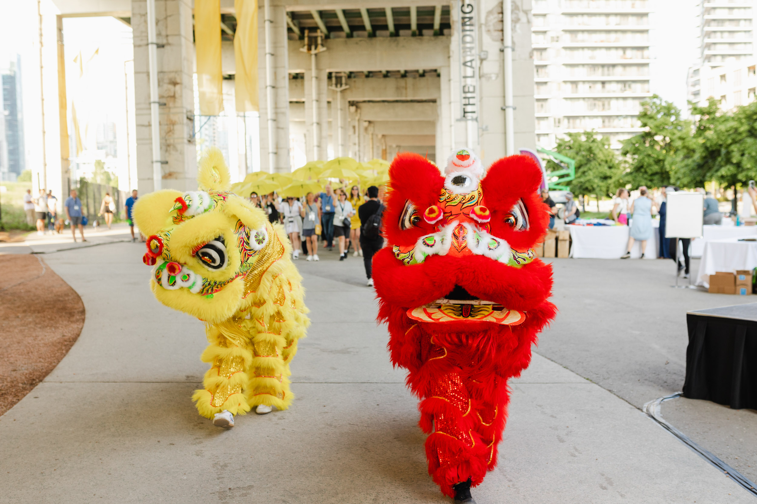 Two Chinese lions parading on a sidewalk during a conference.