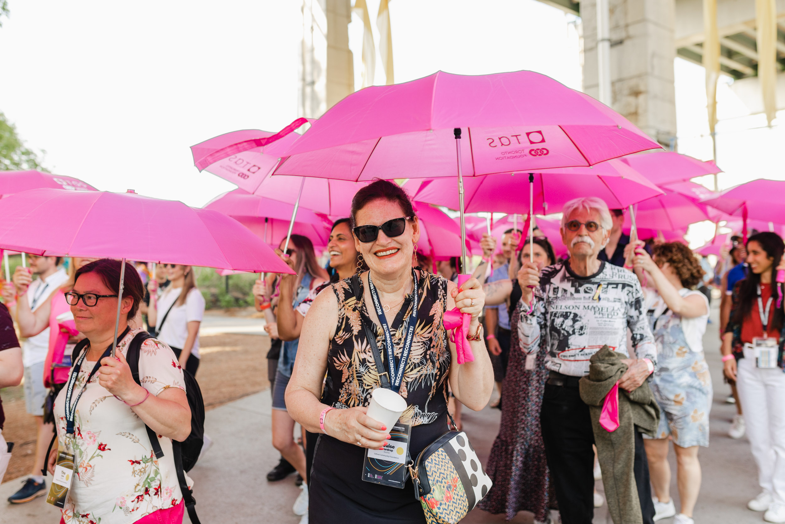 Conference attendees with pink umbrellas.