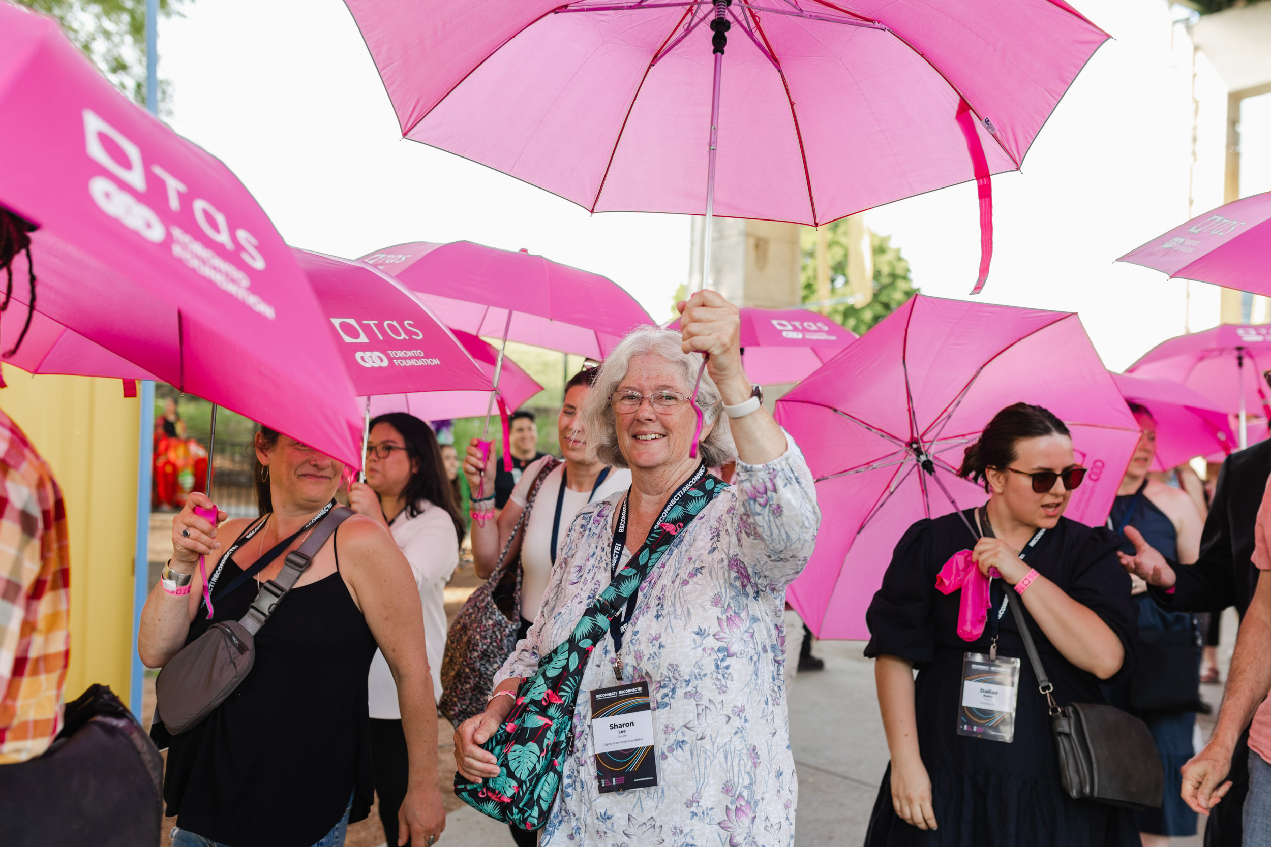 Conference attendees with pink umbrellas.