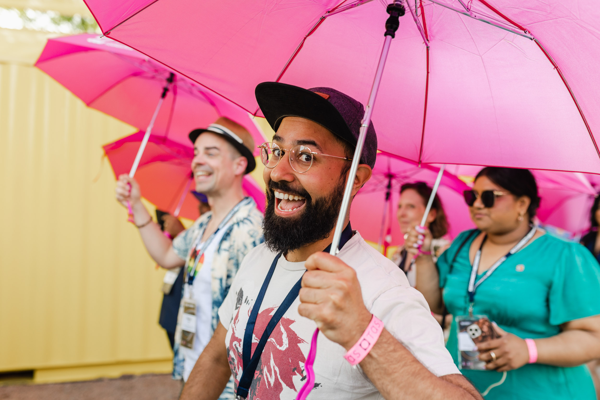 Conference attendees holding pink umbrellas.