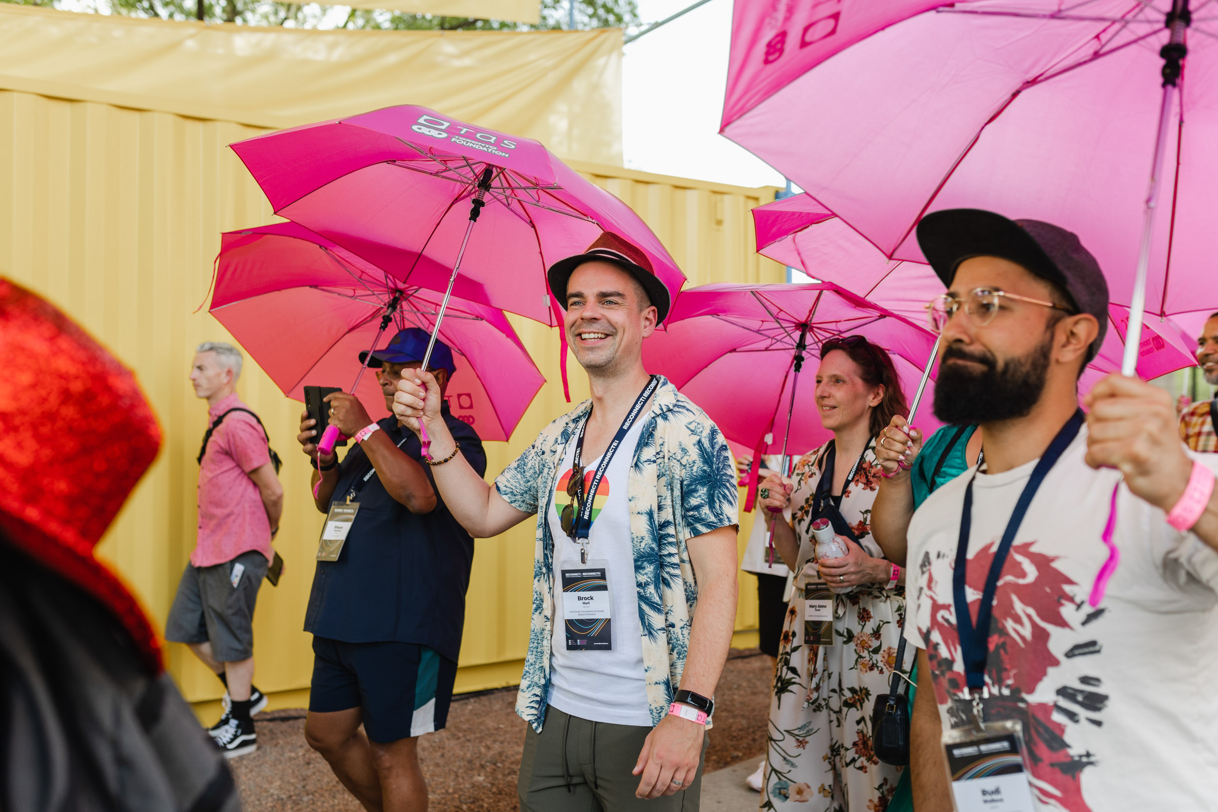 Conference attendees holding pink umbrellas.
