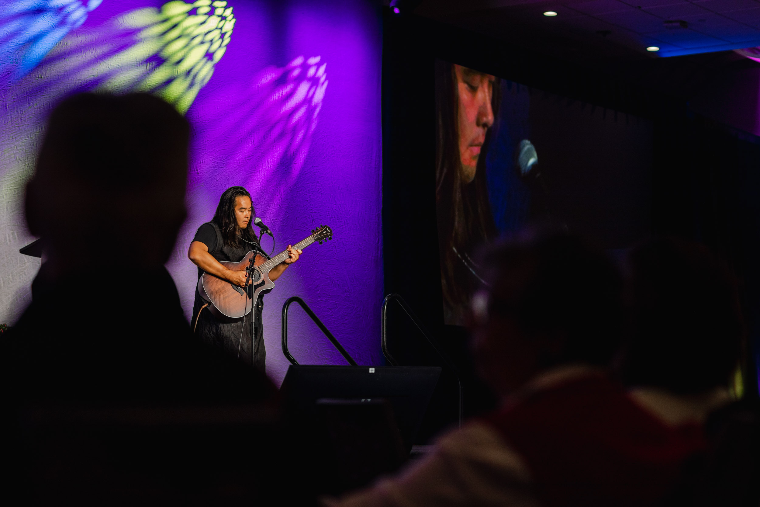 A woman performing with an acoustic guitar at a conference.