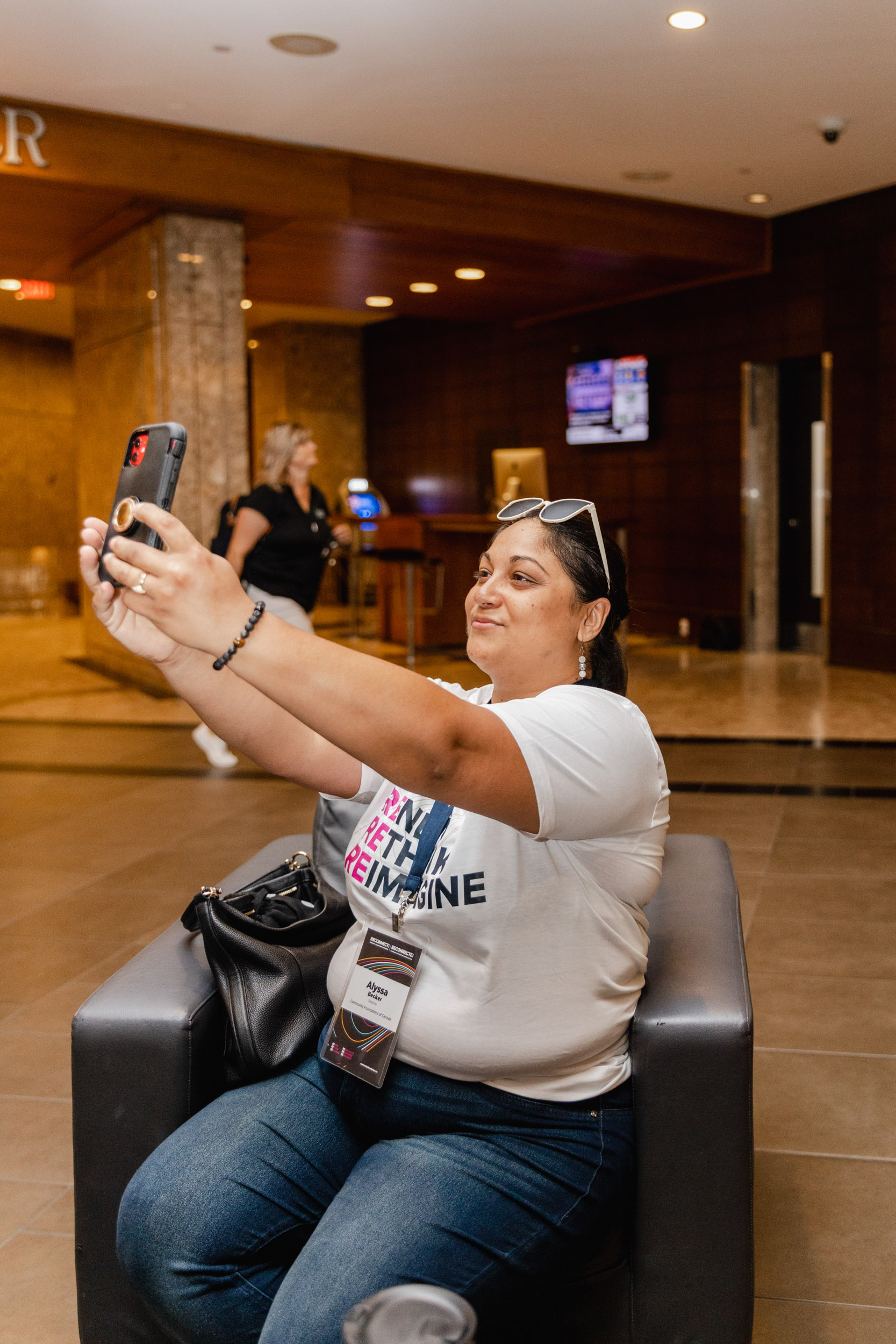 A woman capturing a conference moment with a selfie in a hotel lobby.