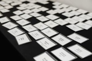 A table full of place cards on a black table at a grand opening event.