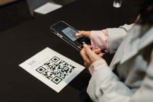A person using a smartphone to scan a QR code at a grand opening event.