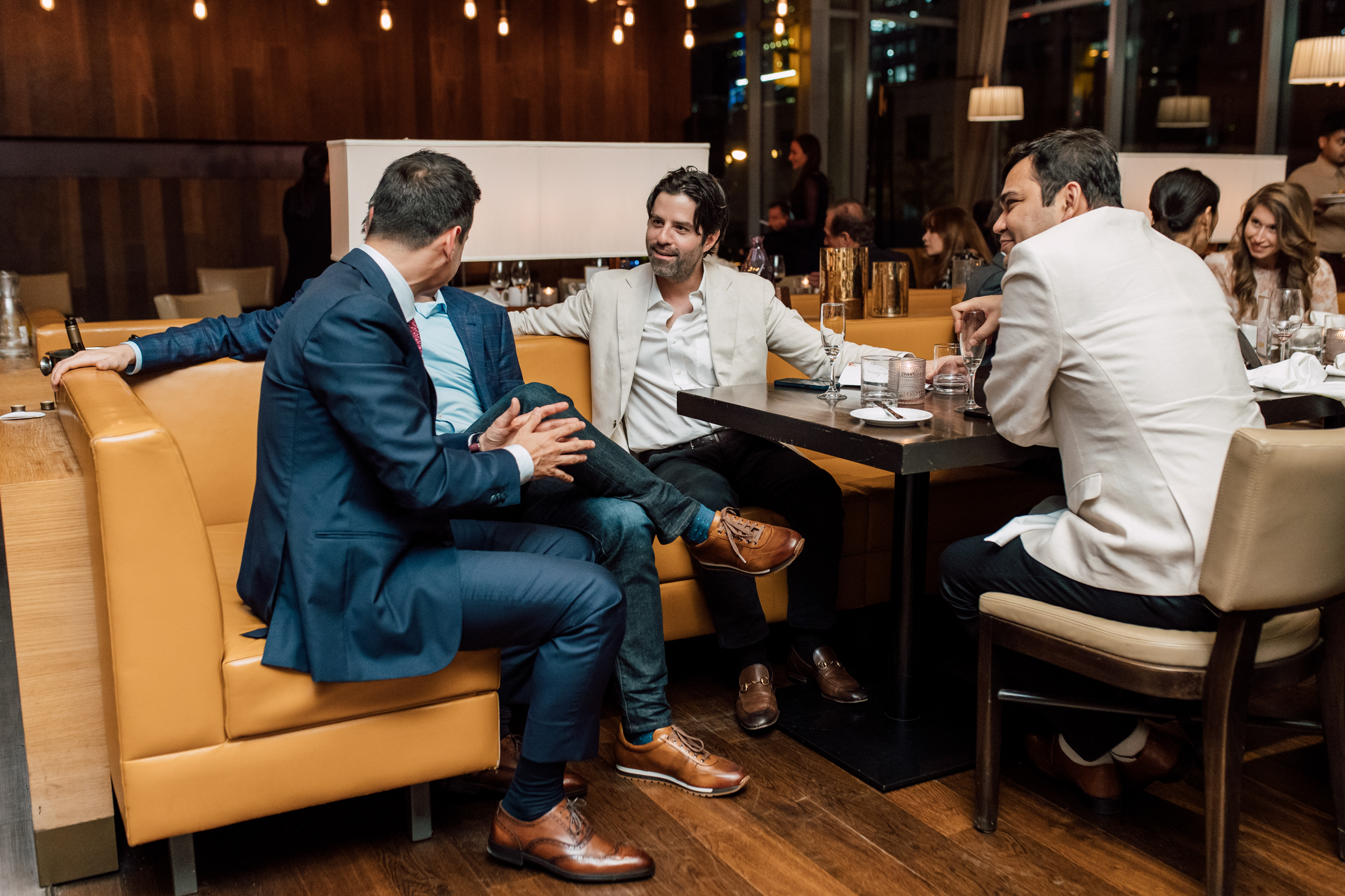 A group of men celebrating their graduation at a table in a restaurant, captured through event photography.