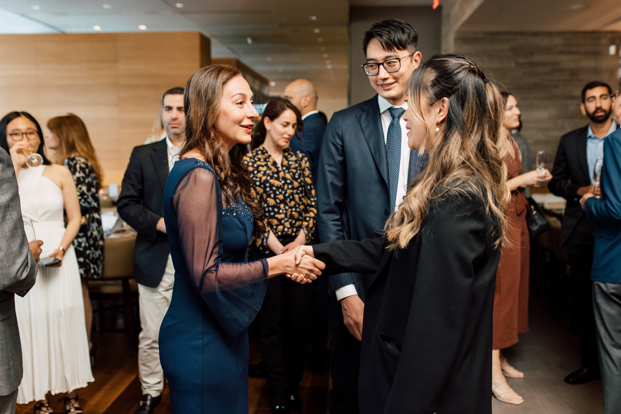 Group of people shaking hands at a graduation event.