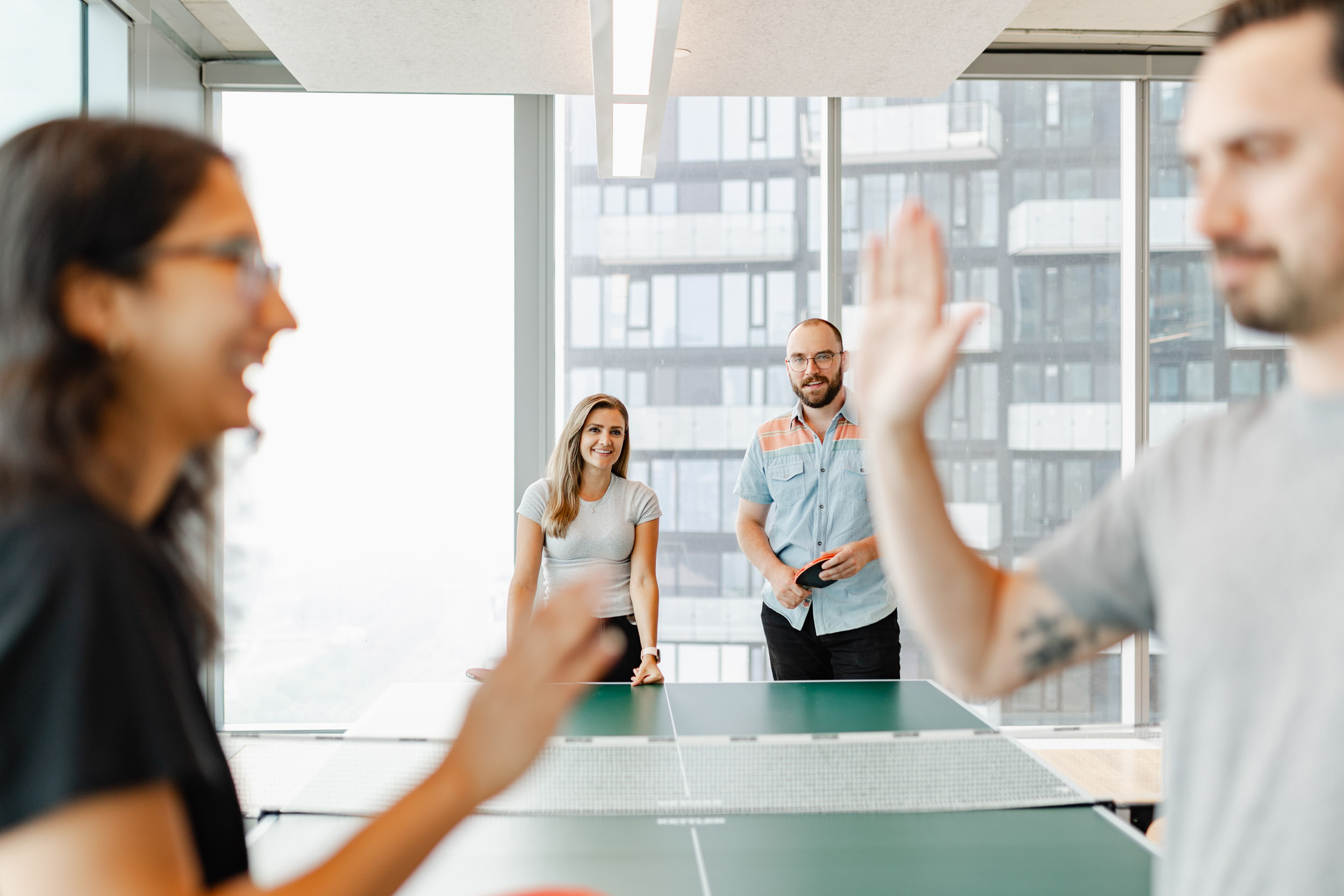 A group of people playing ping pong in the Index Exchange office.
