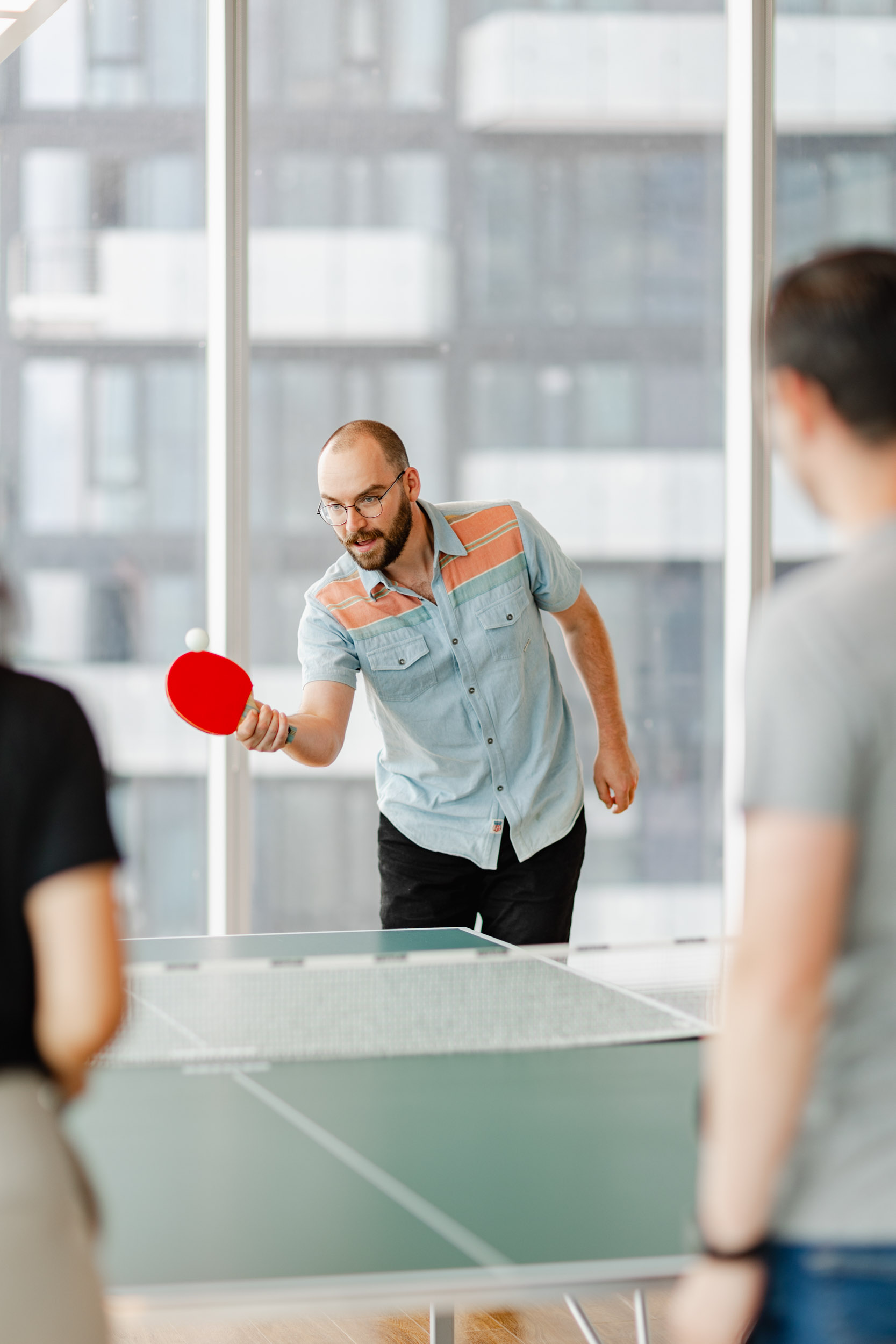 A group of individuals engaging in a game of ping pong at Index Exchange's office.