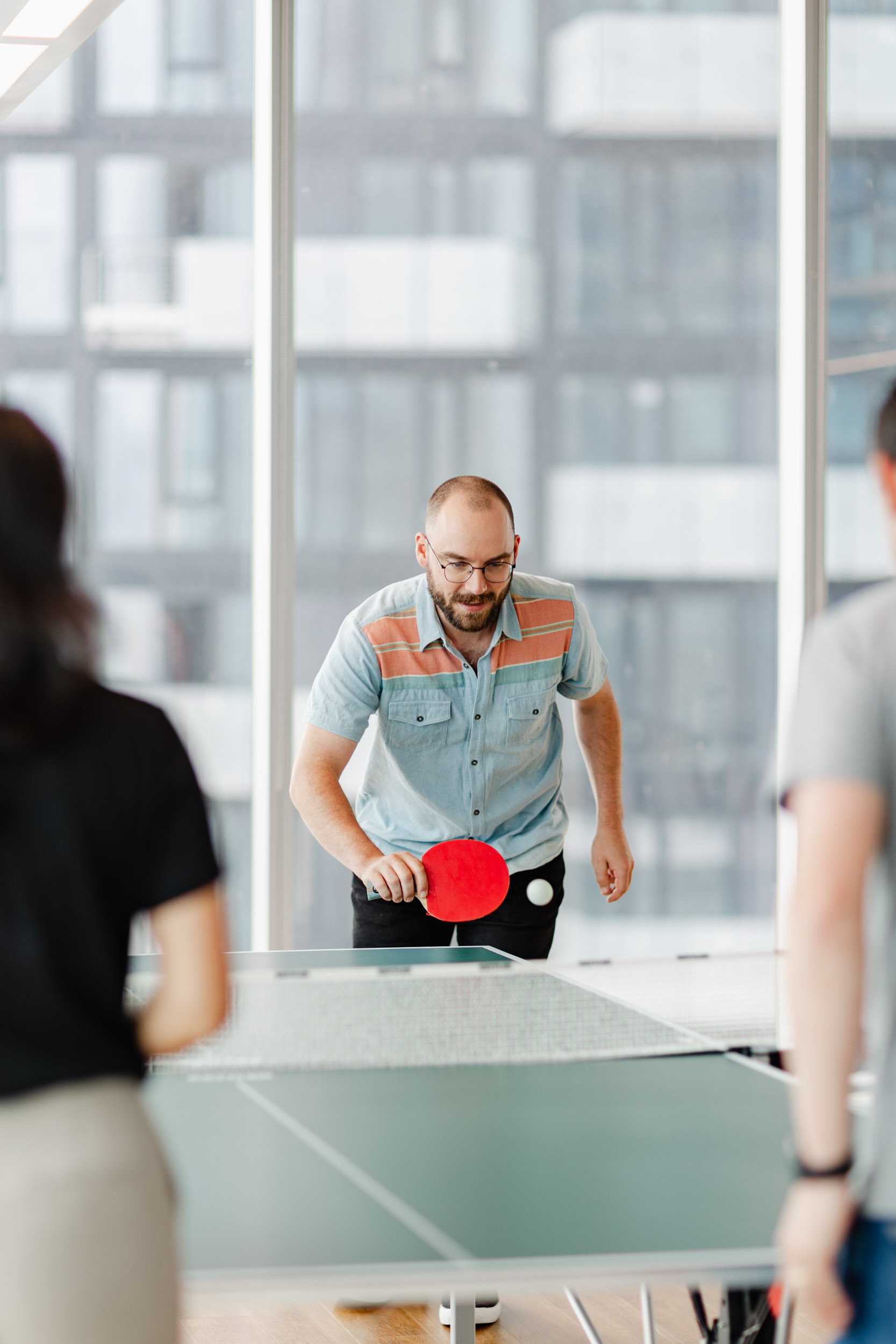Employees at Index Exchange engage in a competitive game of ping pong within their office environment.