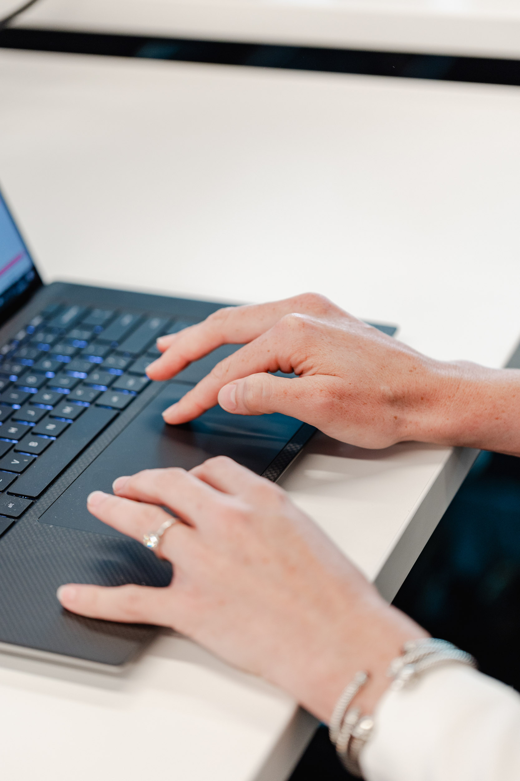 A woman's hands engaging in Index Exchange while typing on a laptop.