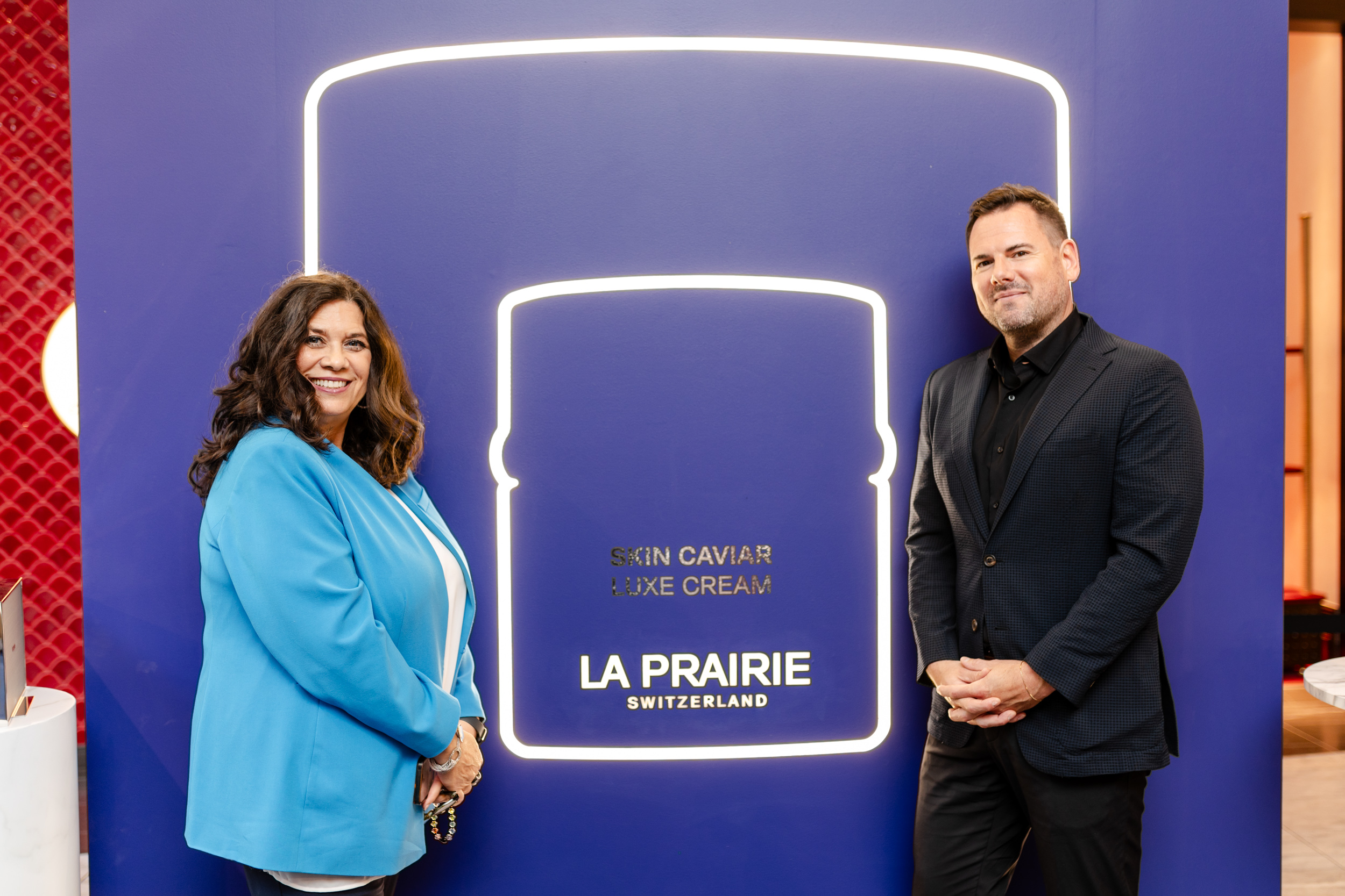 Two people standing in front of a sign that says la prairie.