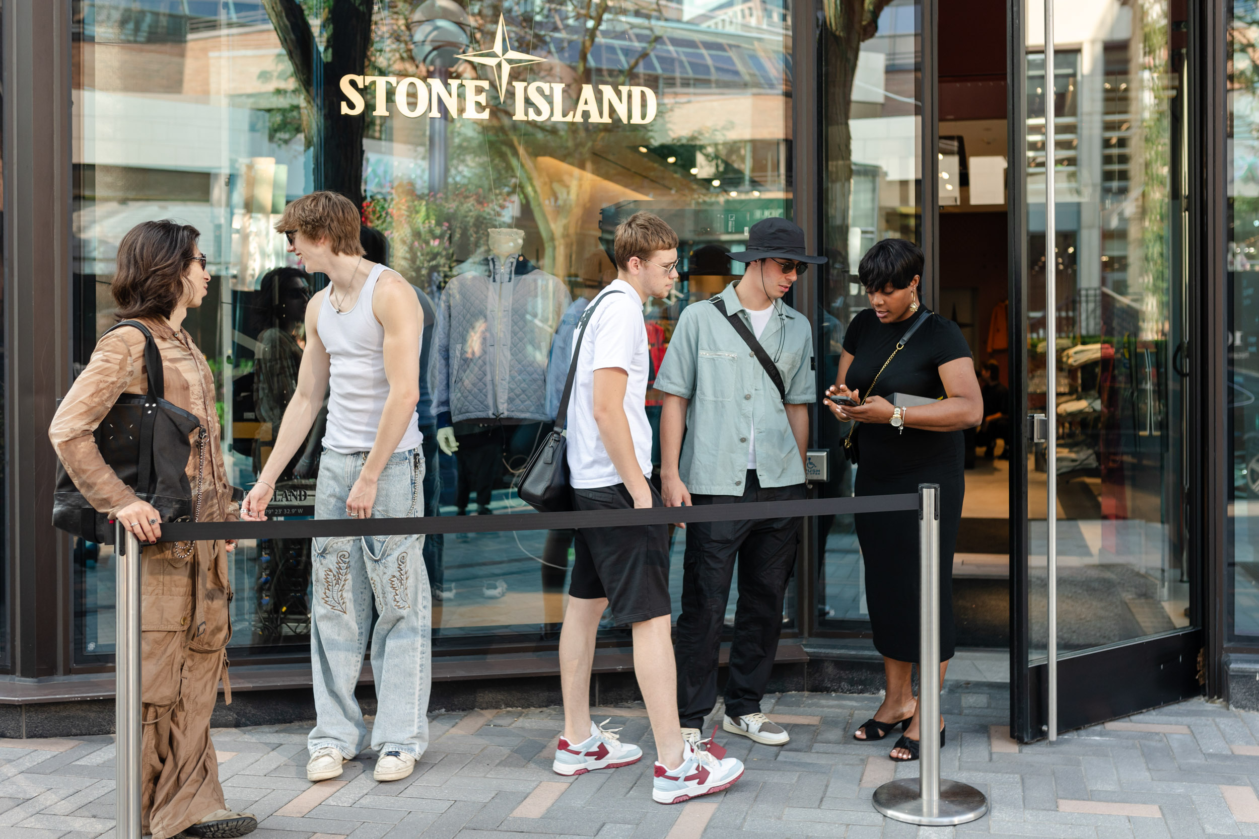 A group of people standing in front of the Stone Island store.
