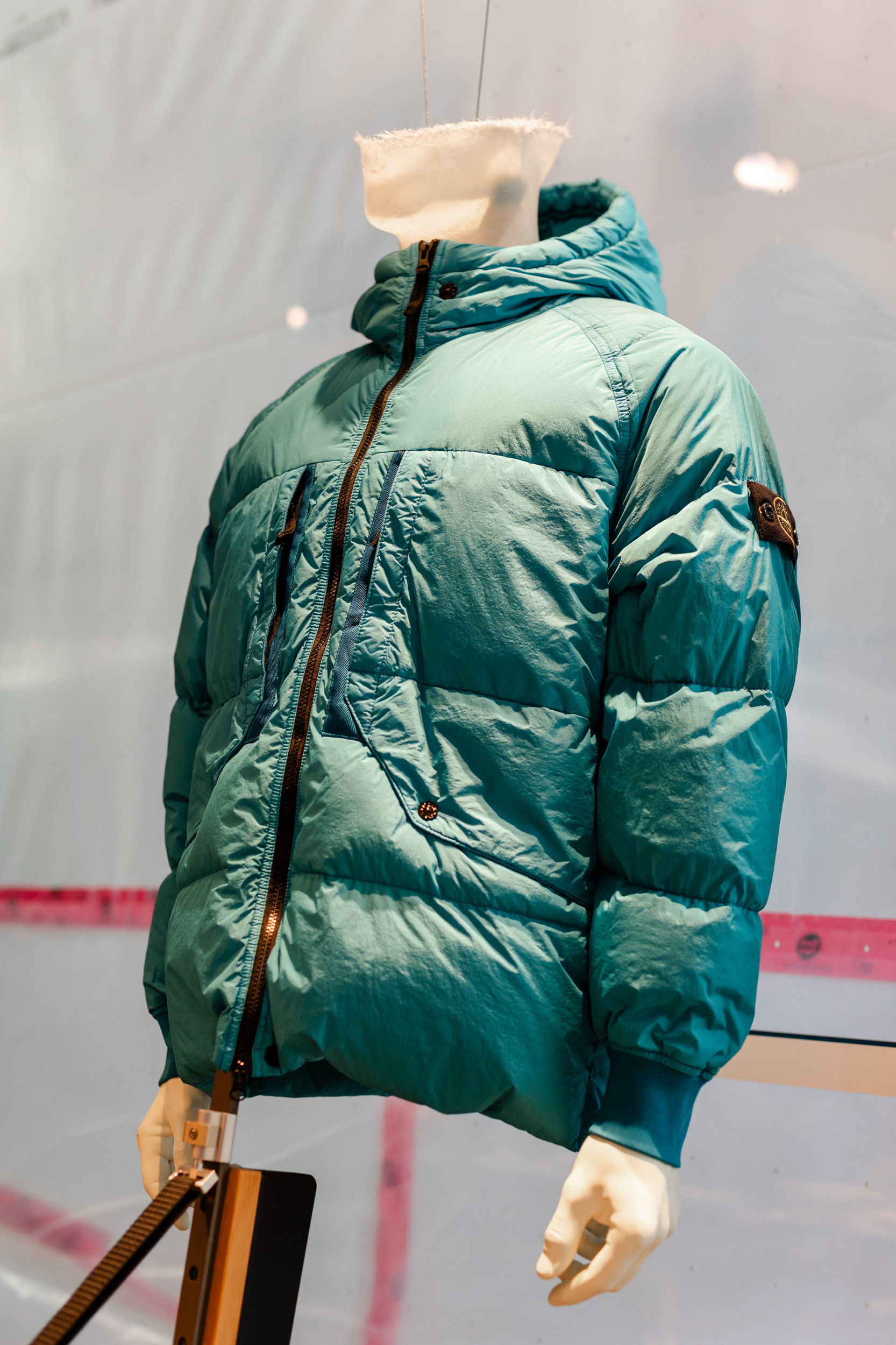 stone island puffer jacket is displayed in a display case.