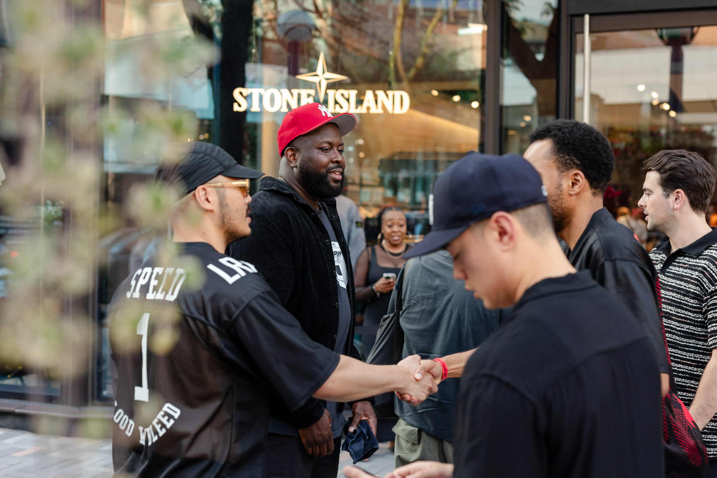 A group of men shaking hands in front of the Stone Island store