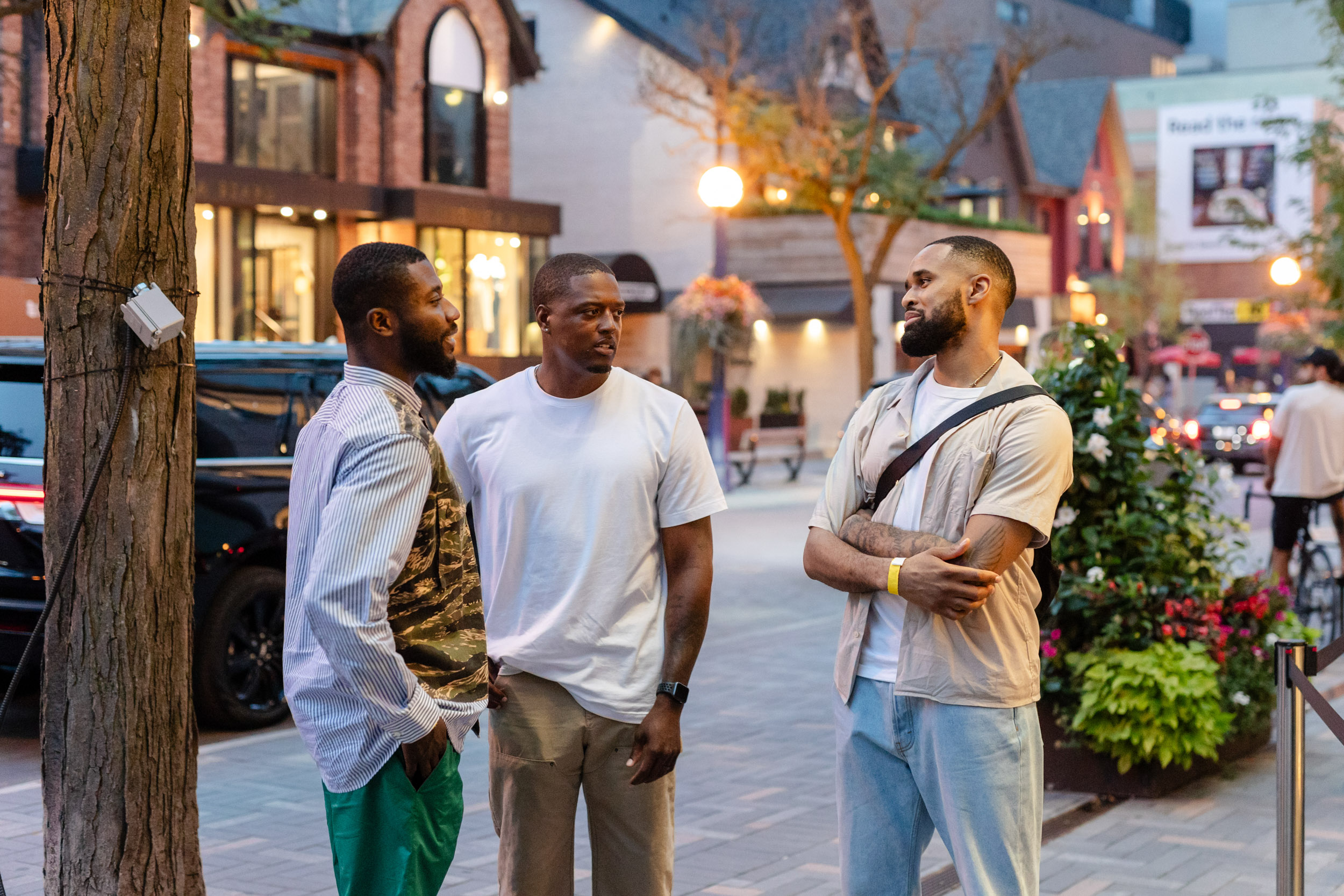 Three men standing on a sidewalk talking to each other