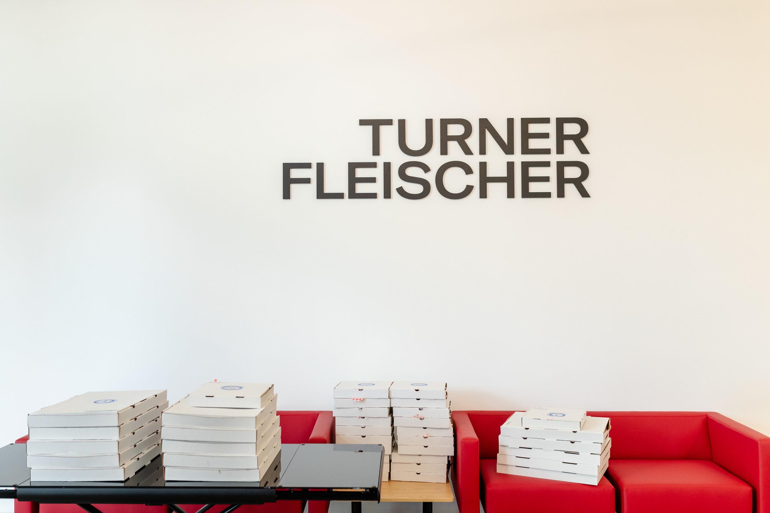 A room with red couches and a wall that says Turner Flescher