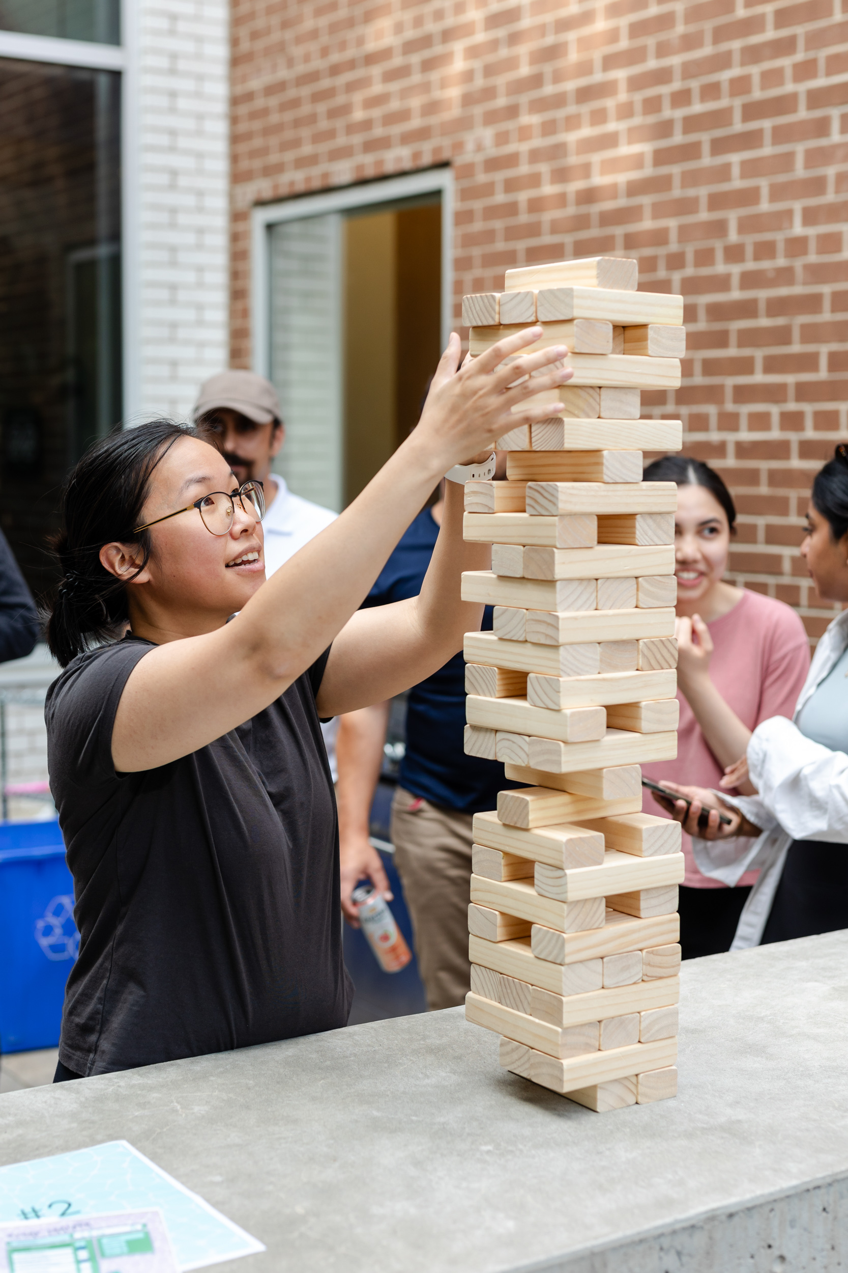 Social Event: A group of people playing a game of Jenga, captured in photography.