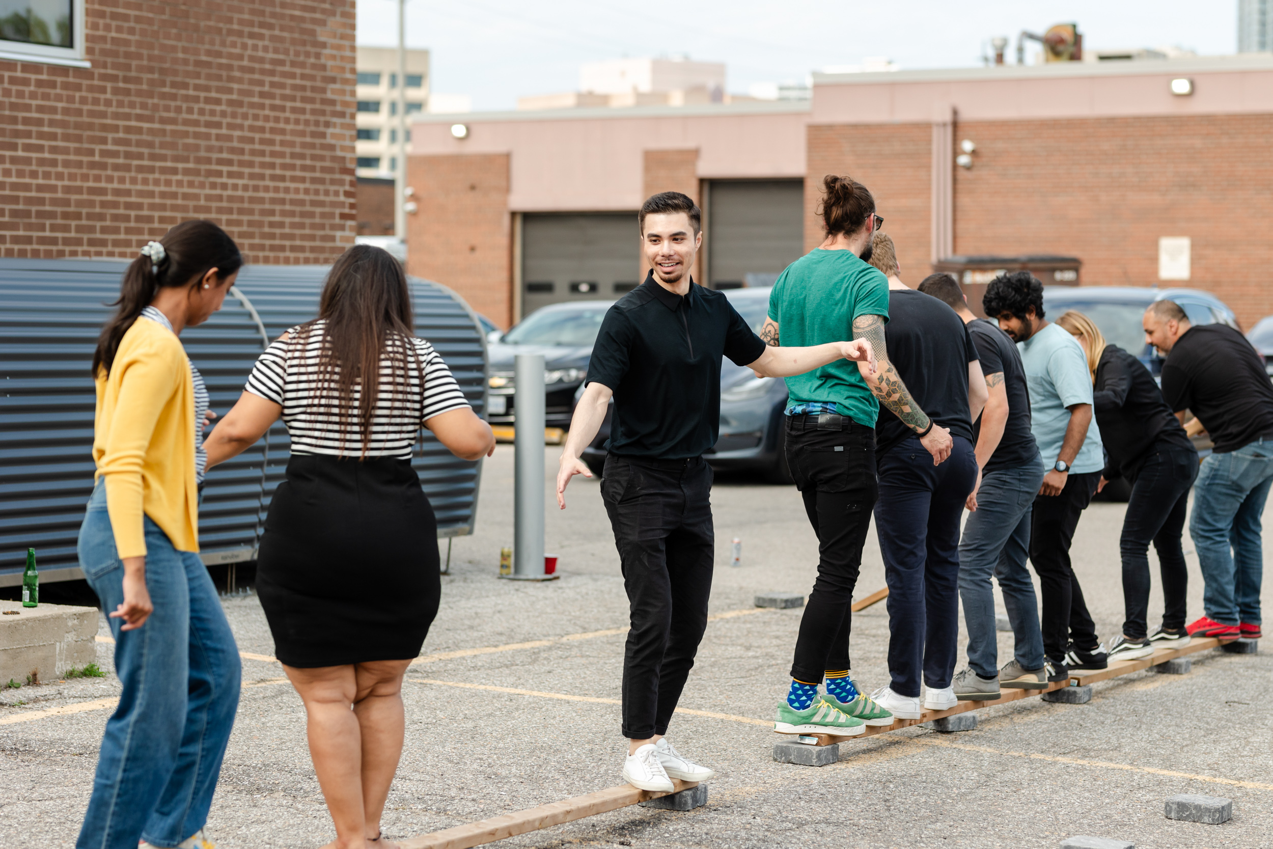 A crowd of individuals posing on wooden planks in a parking lot at a social gathering.