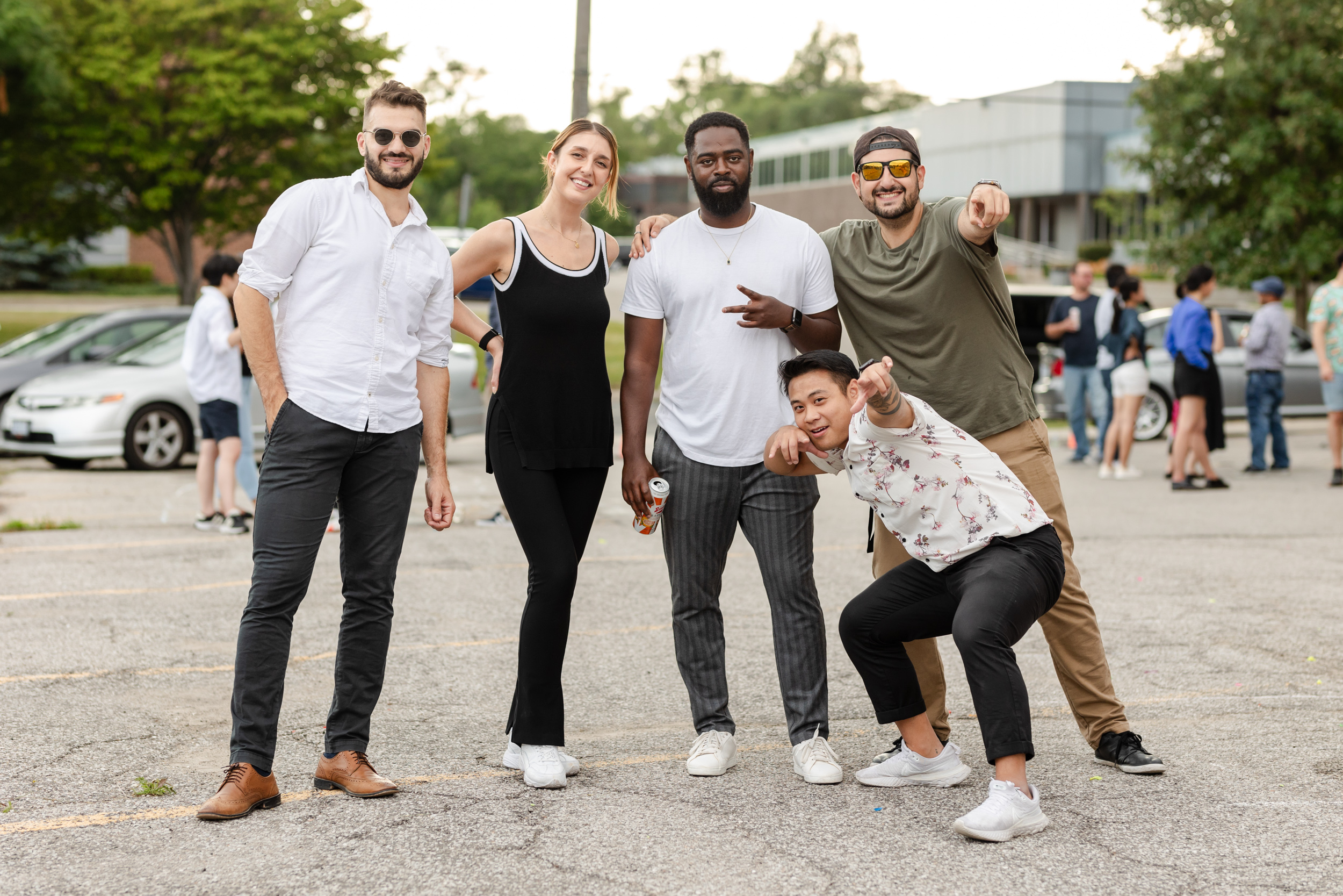Social Event Photography: People posing for a group photo in a parking lot.