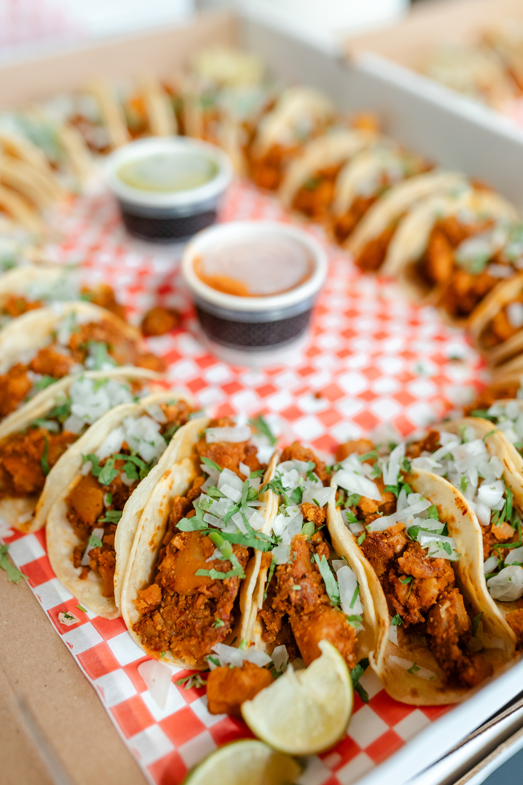 A tray of tacos sitting on top of a checkered tablecloth.