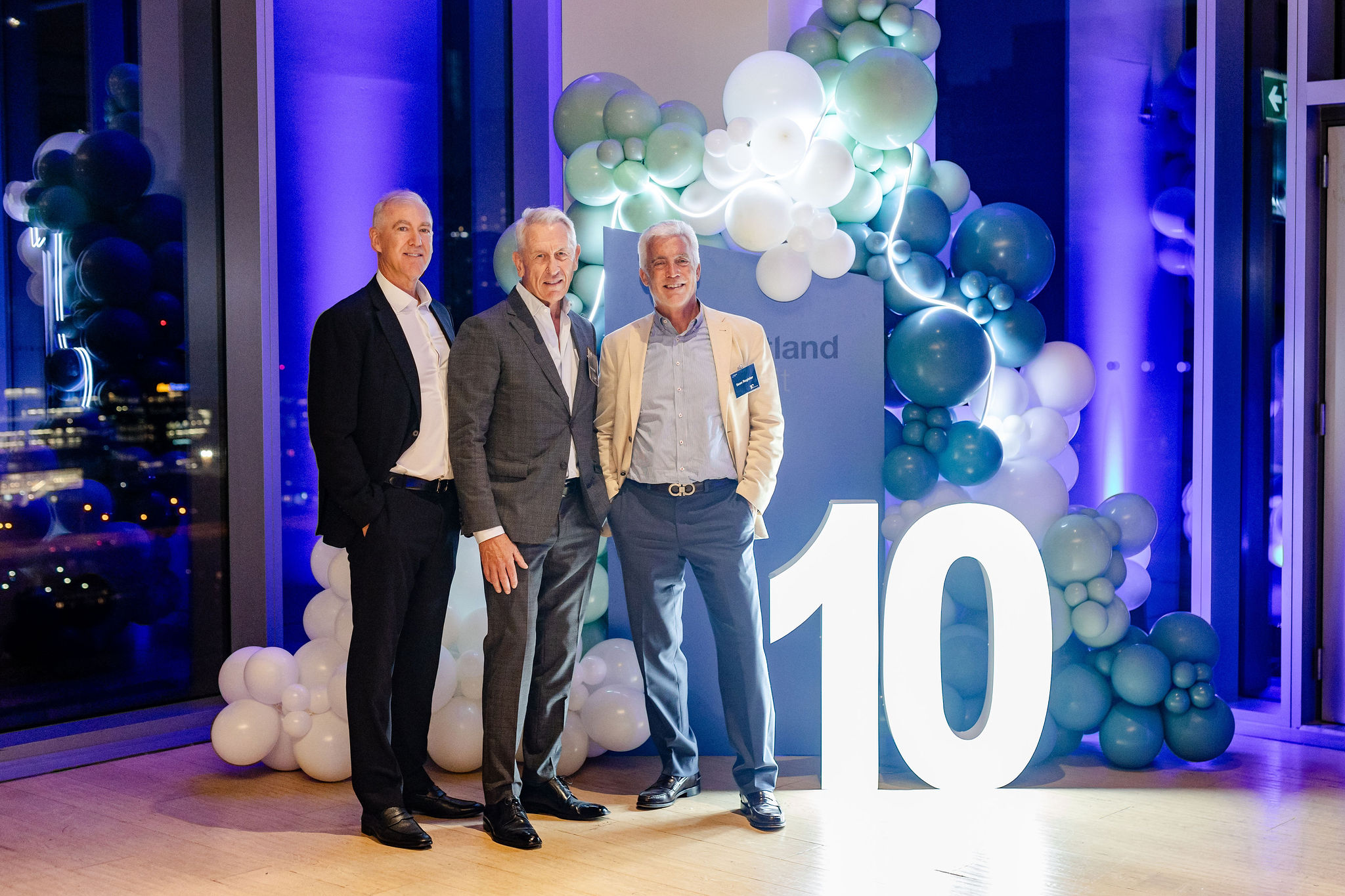 Three men posing in front of a number 10.