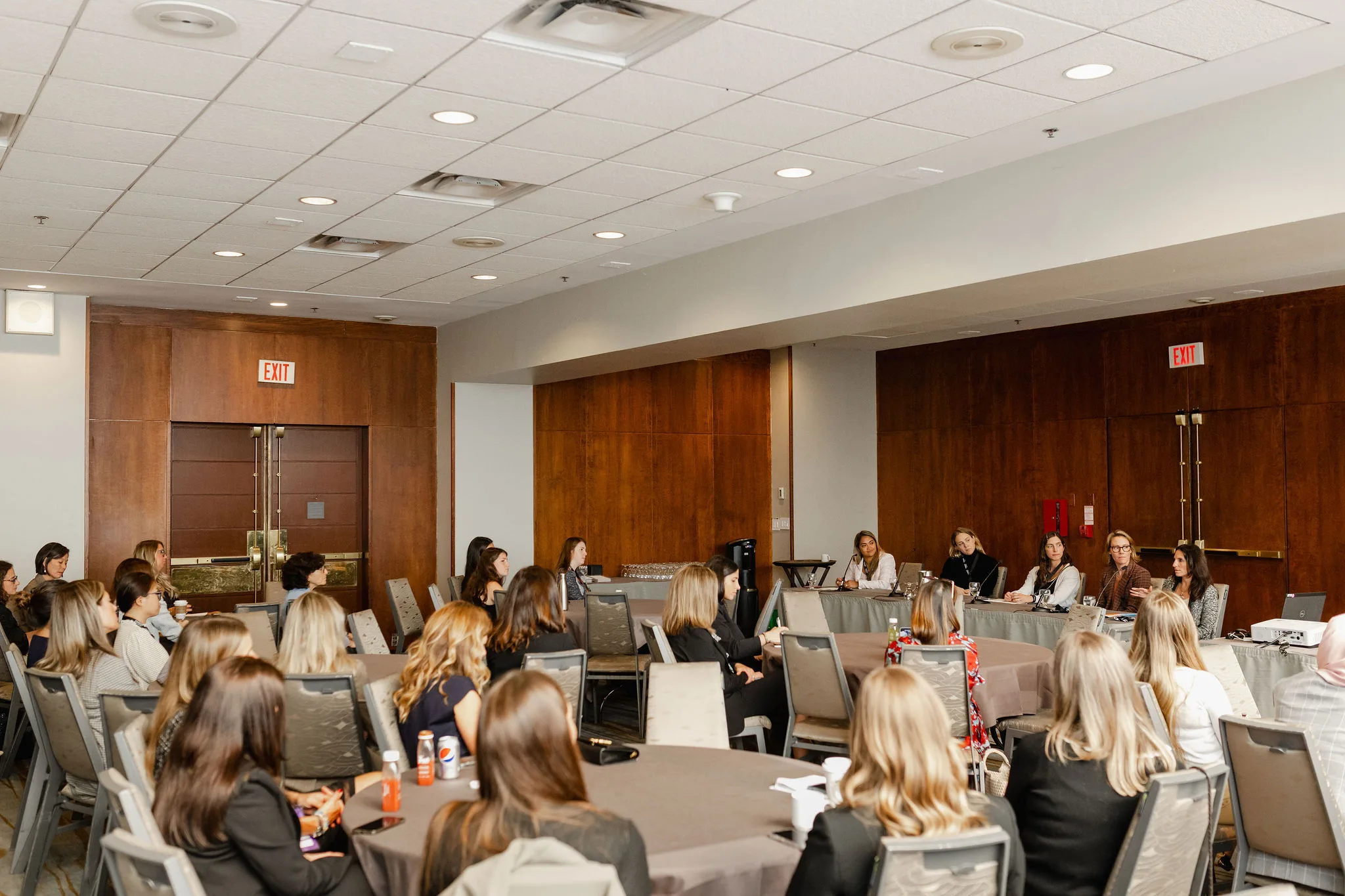 A group of women sitting at tables in a conference room. (Keywords: women, conference room)