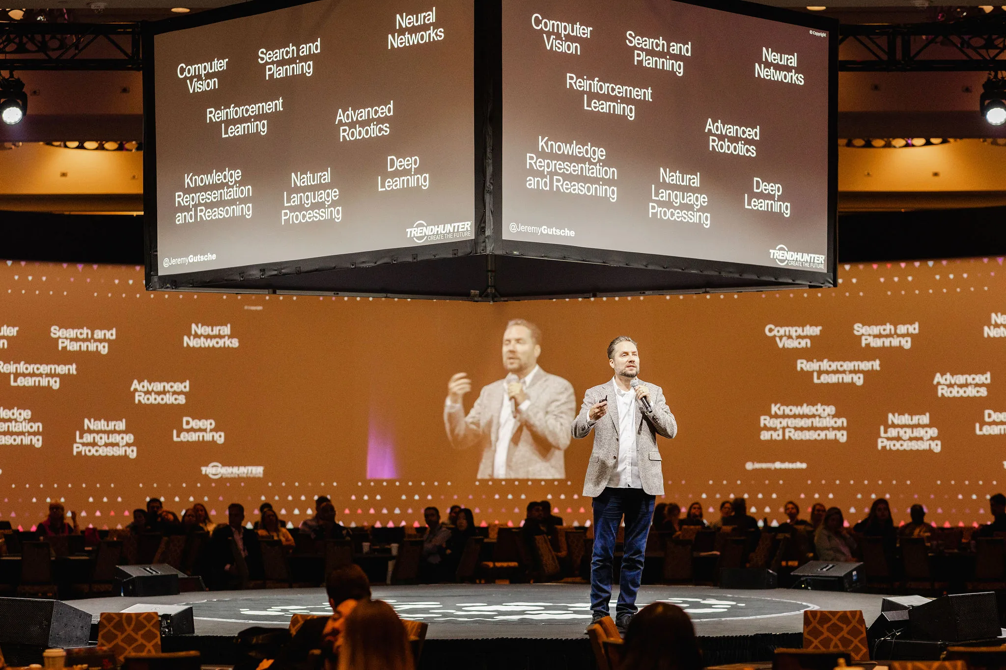 A man on stage, large screen.