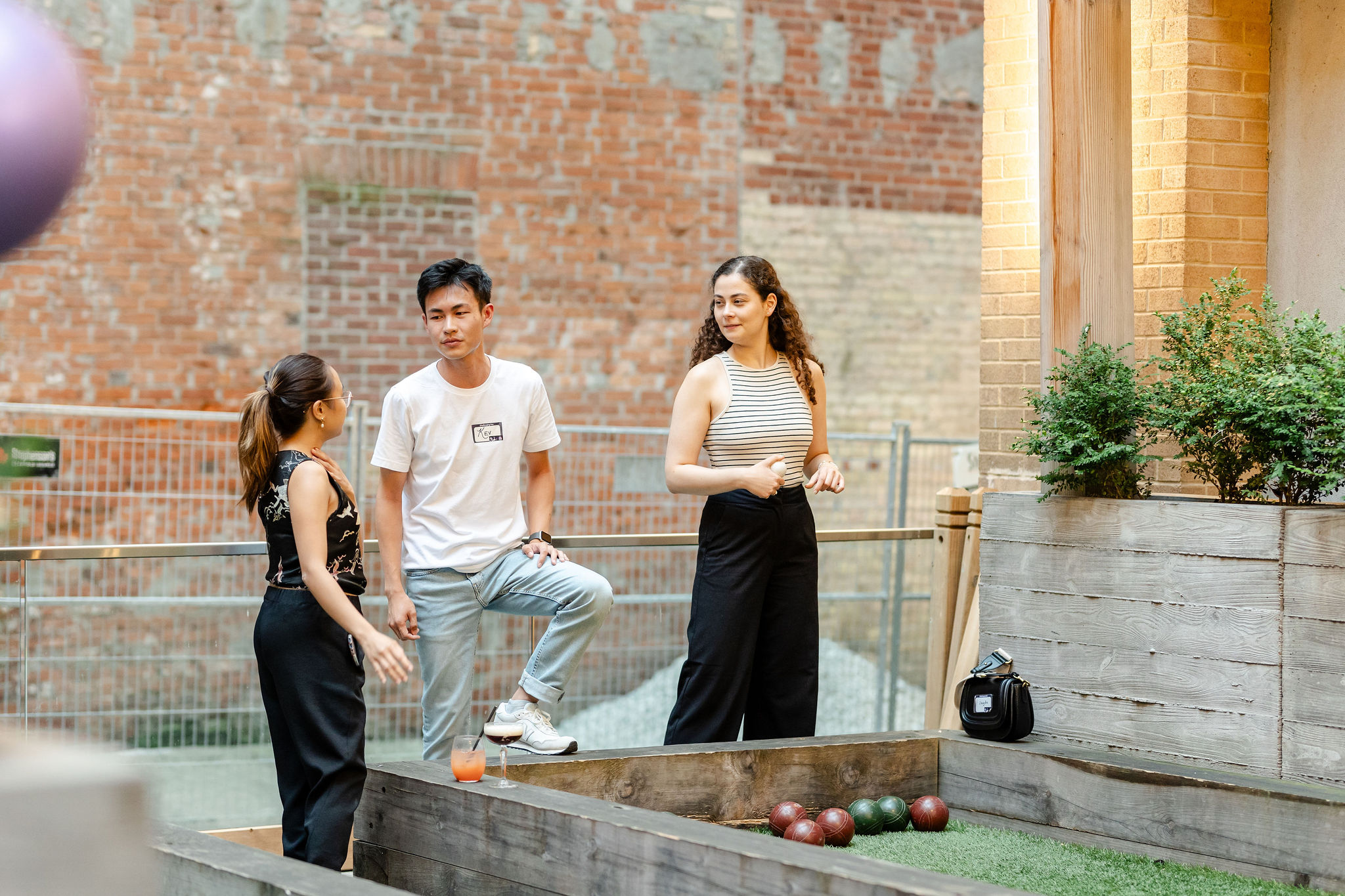 Individuals playing bocce ball in a courtyard.