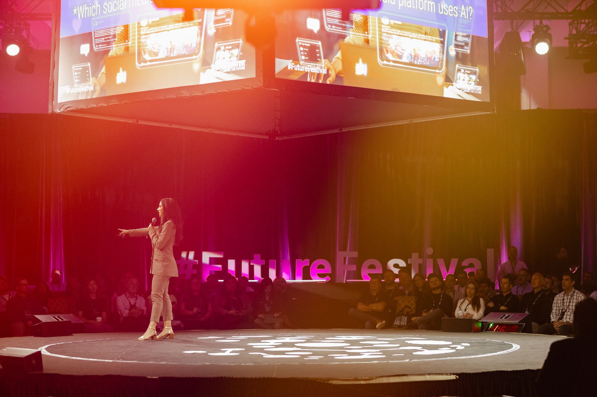 Event photography: A woman standing on stage capturing mesmerizing moments under the spotlight, with a captivating large screen as the backdrop.