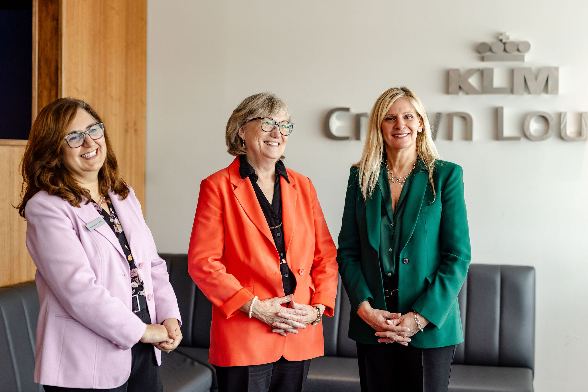 Three women standing in front of a sign that says klm crown lounge.