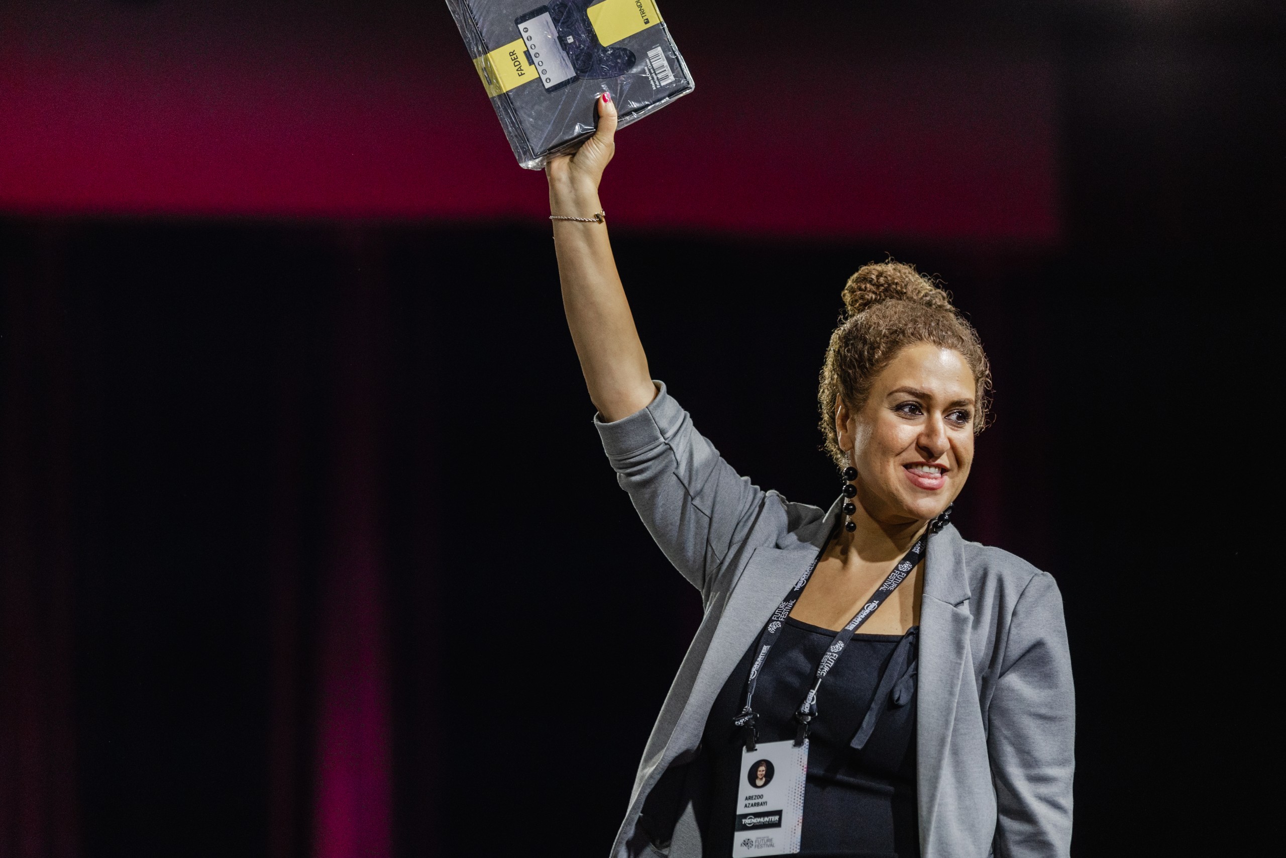 A woman holding up a book during an event on stage.
