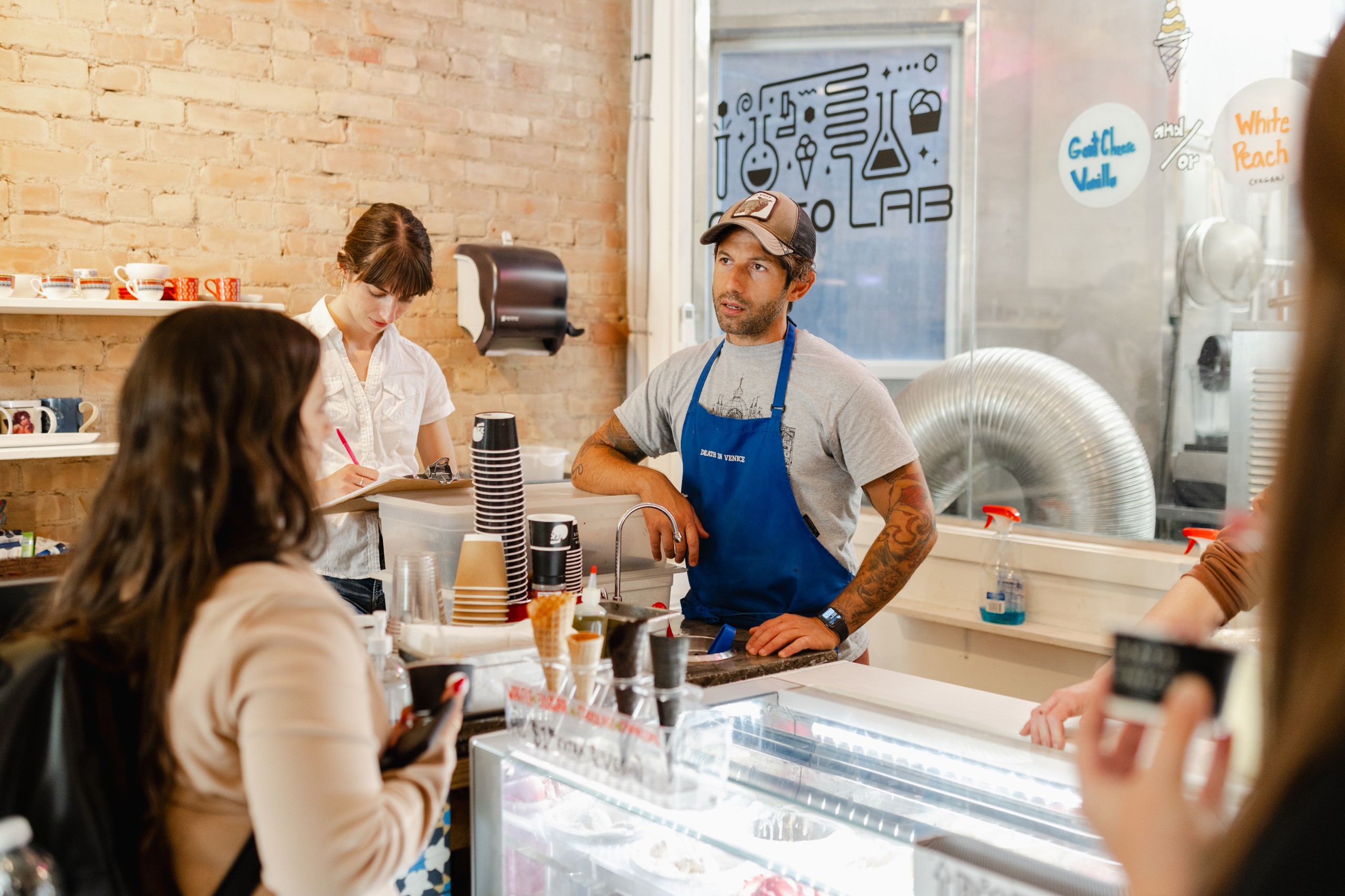 A group of people standing at a counter at an ice cream shop captured through event photography.