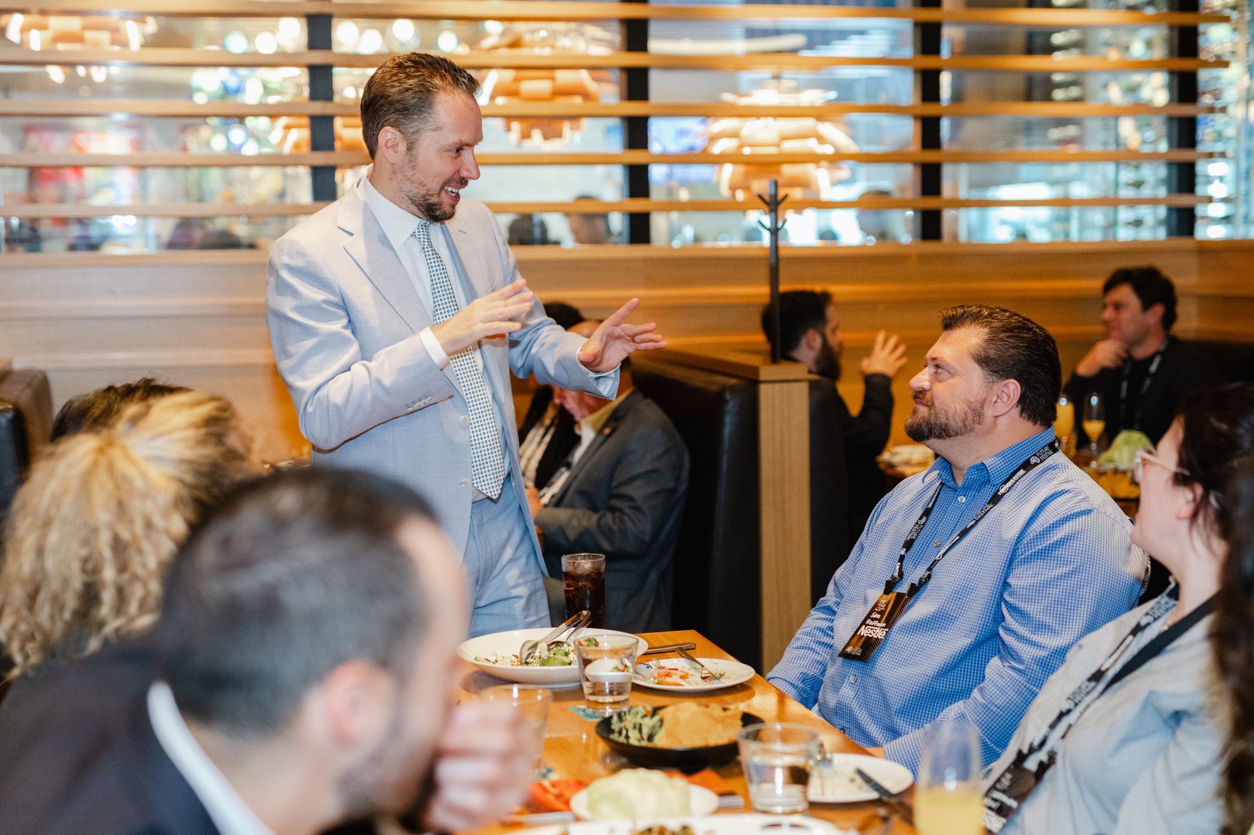 A man delivering a speech to a group of people at a restaurant, captured through event photography.