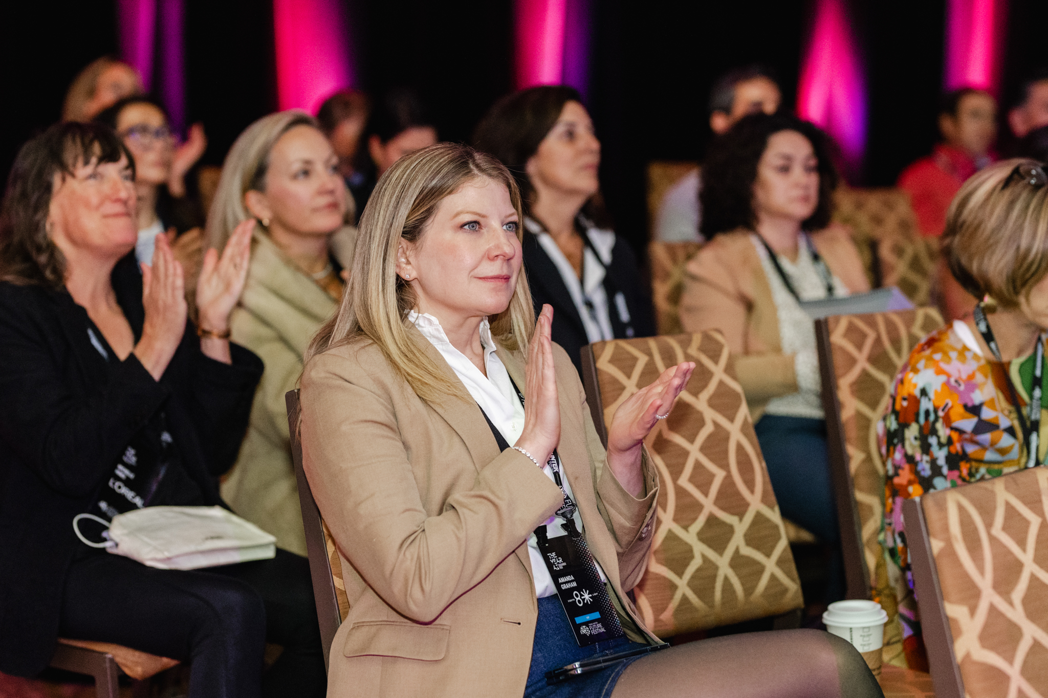 An event photography capturing a group of women clapping at a conference.